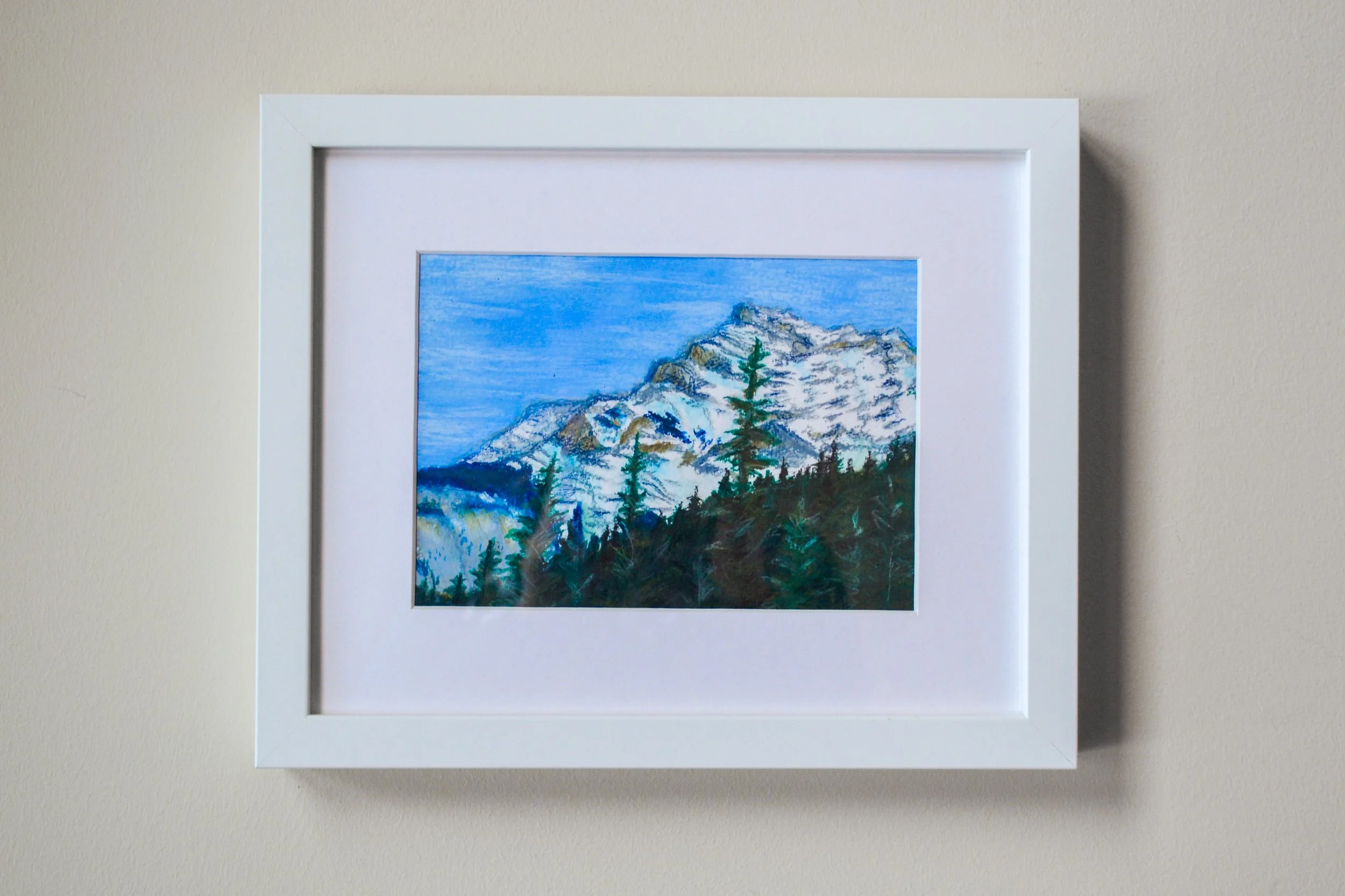 Framed painting of snow-capped mountains and pine trees