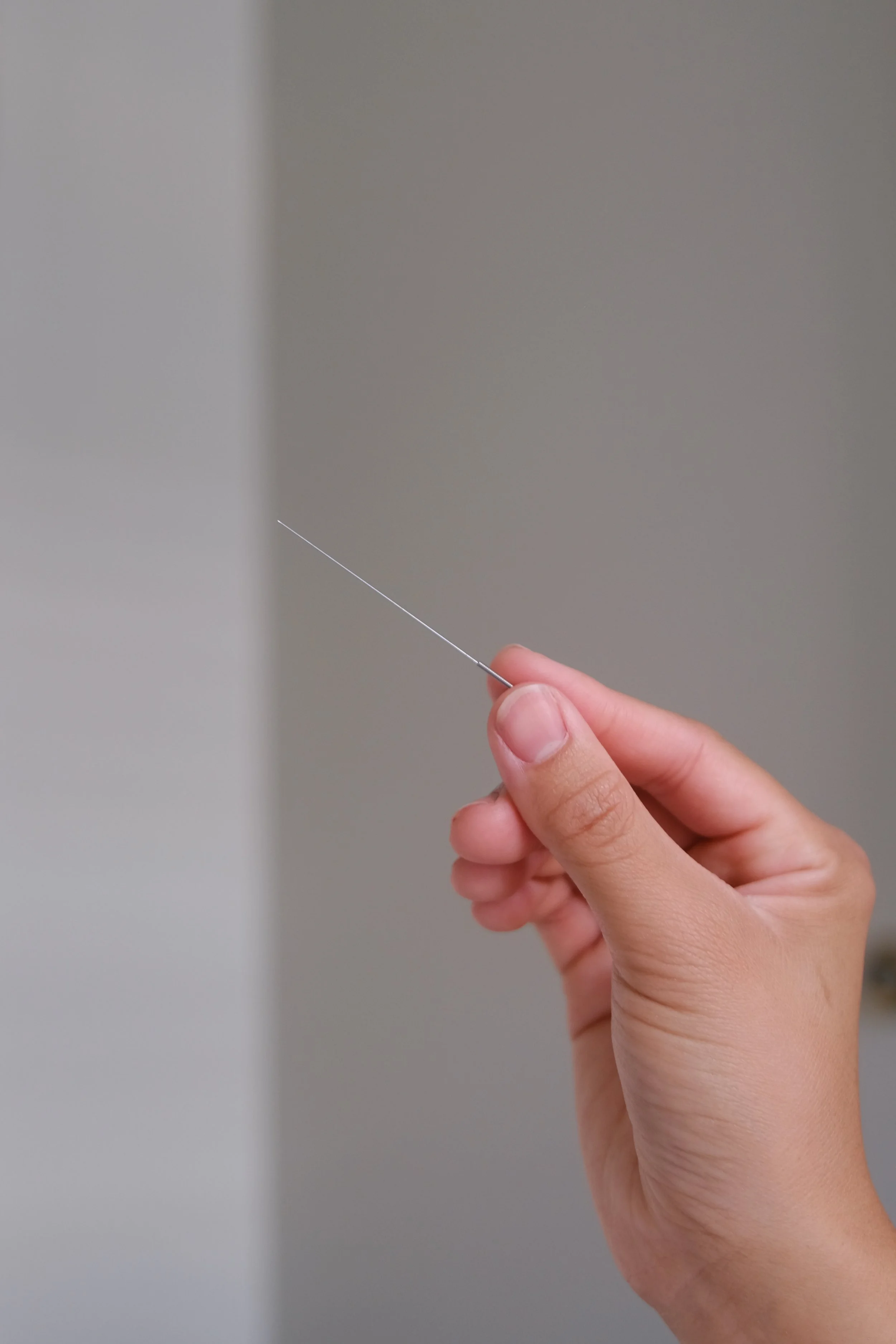 A person administering acupuncture to a patient's arm.