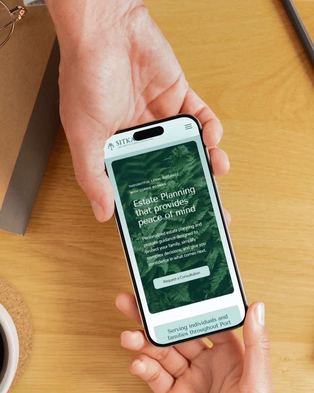 Person holding a smartphone displaying a website for estate planning, with a green background and white text about legal guidance and peace of mind.