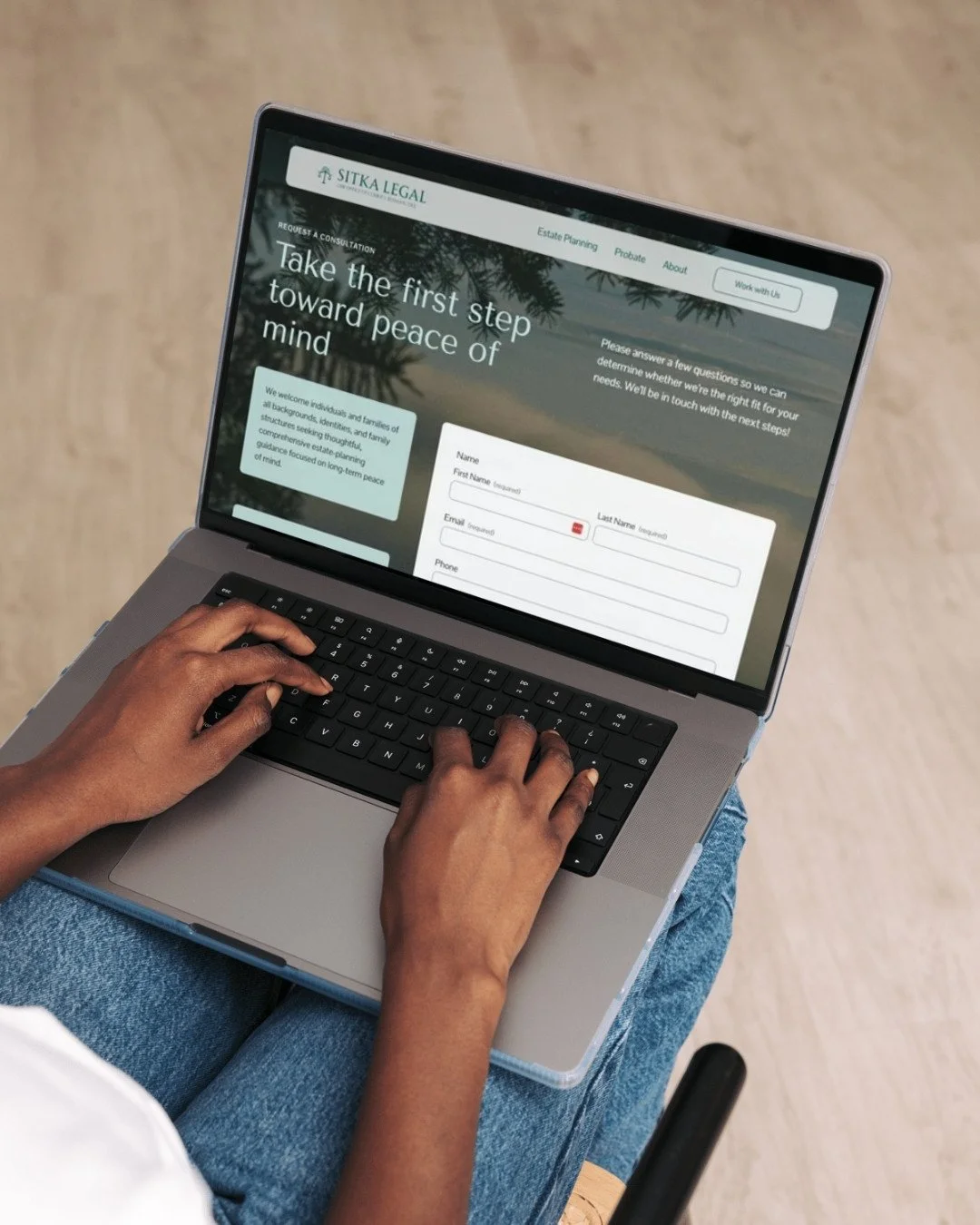 Person using a laptop on their lap, viewing a website called Sitka Legal about estate planning and peace of mind.