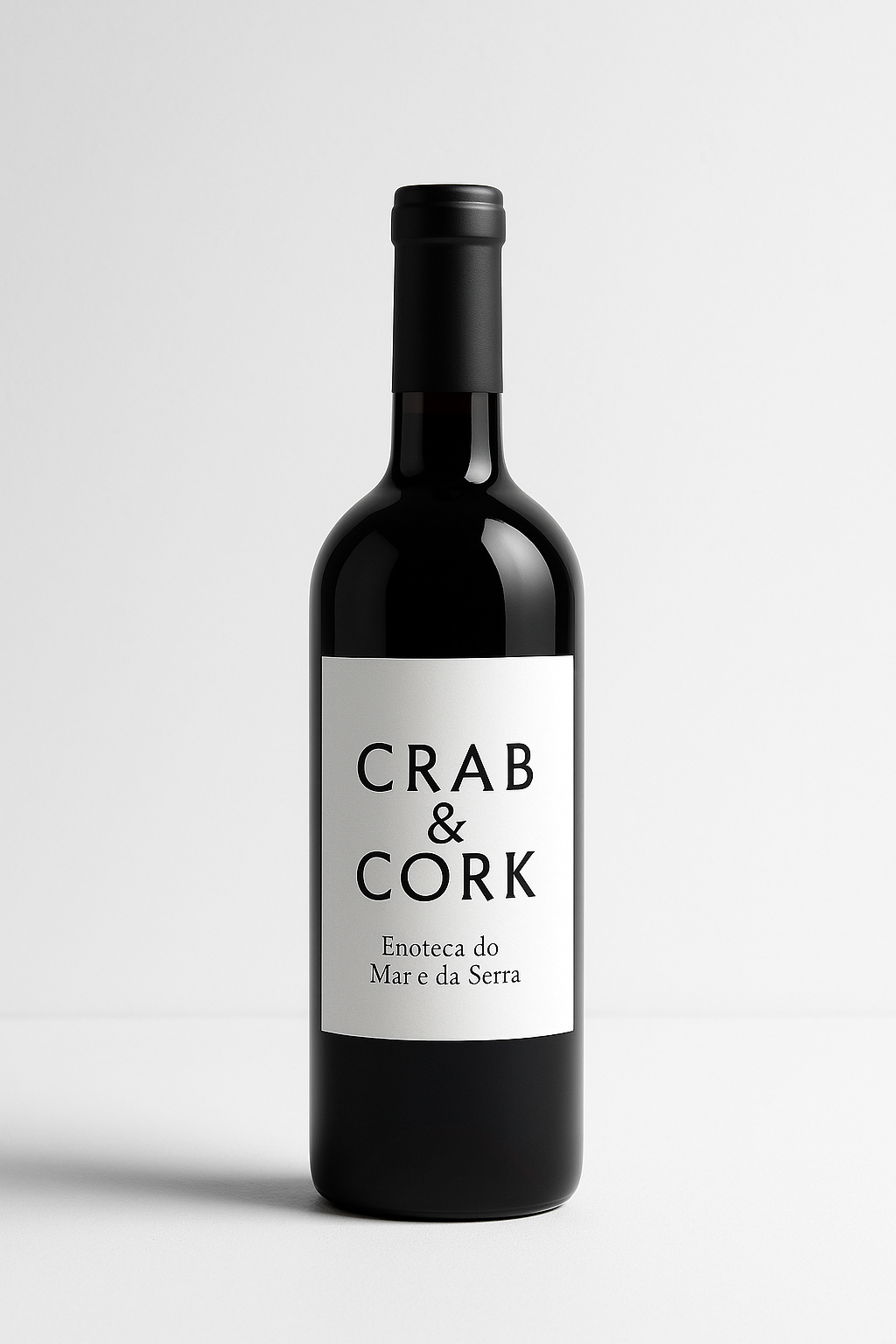A dark glass bottle of wine with a white label that reads 'CRAB & CORK' and smaller text 'Enoteca do Mar e da Serra' against a plain, light background.