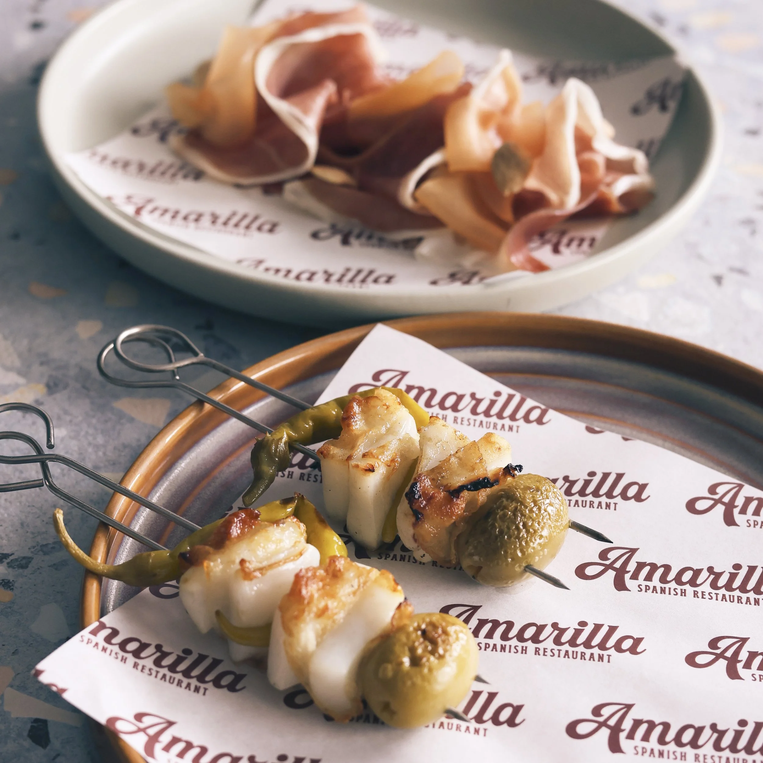 Spanish tapas dishes plated on Amarilla Terrigal restaurant branded paper