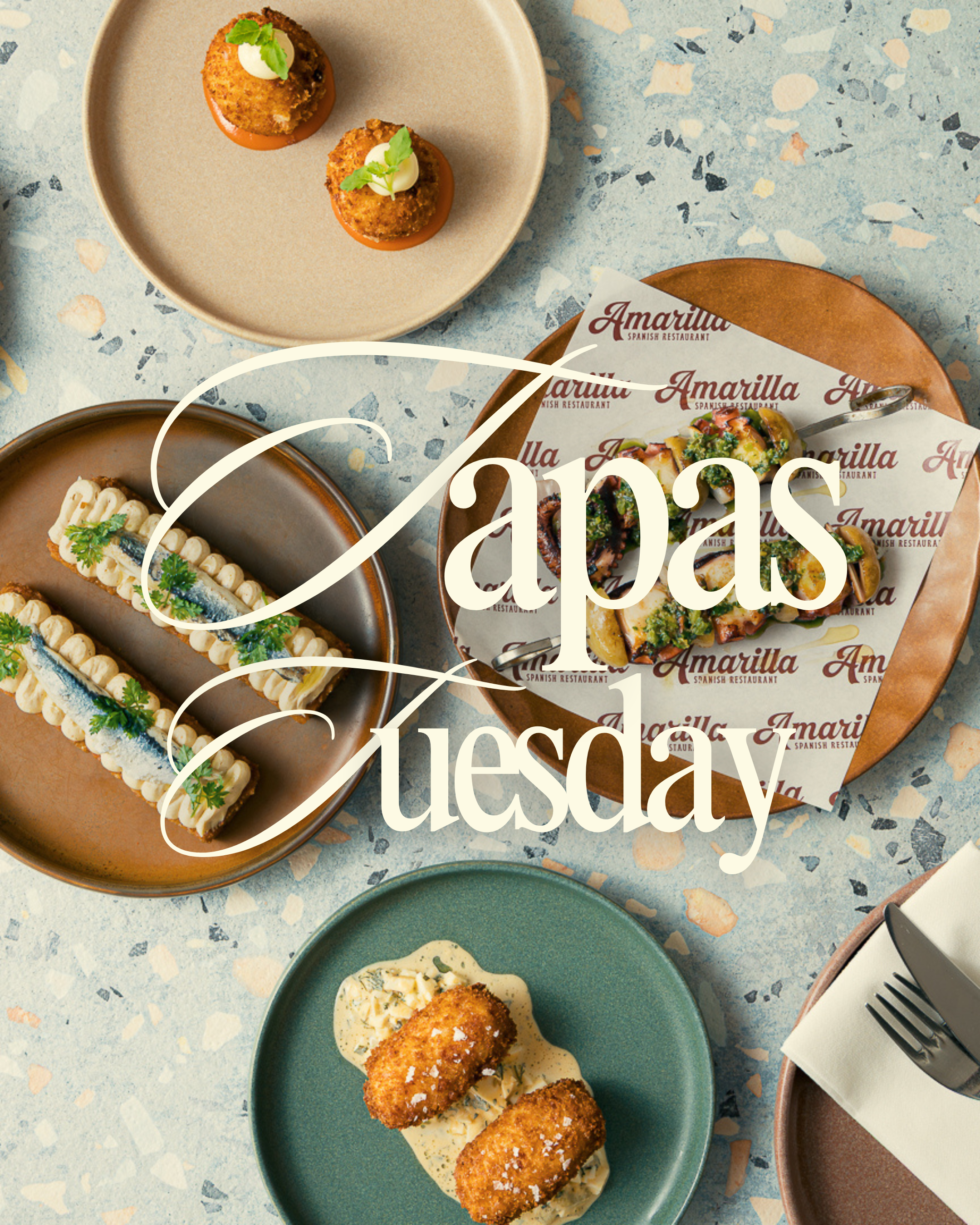 Assorted Spanish tapas dishes served on colorful plates on a terrazzo table, with a menu or promotional material from Amarilla Spanish Restaurant partially visible.