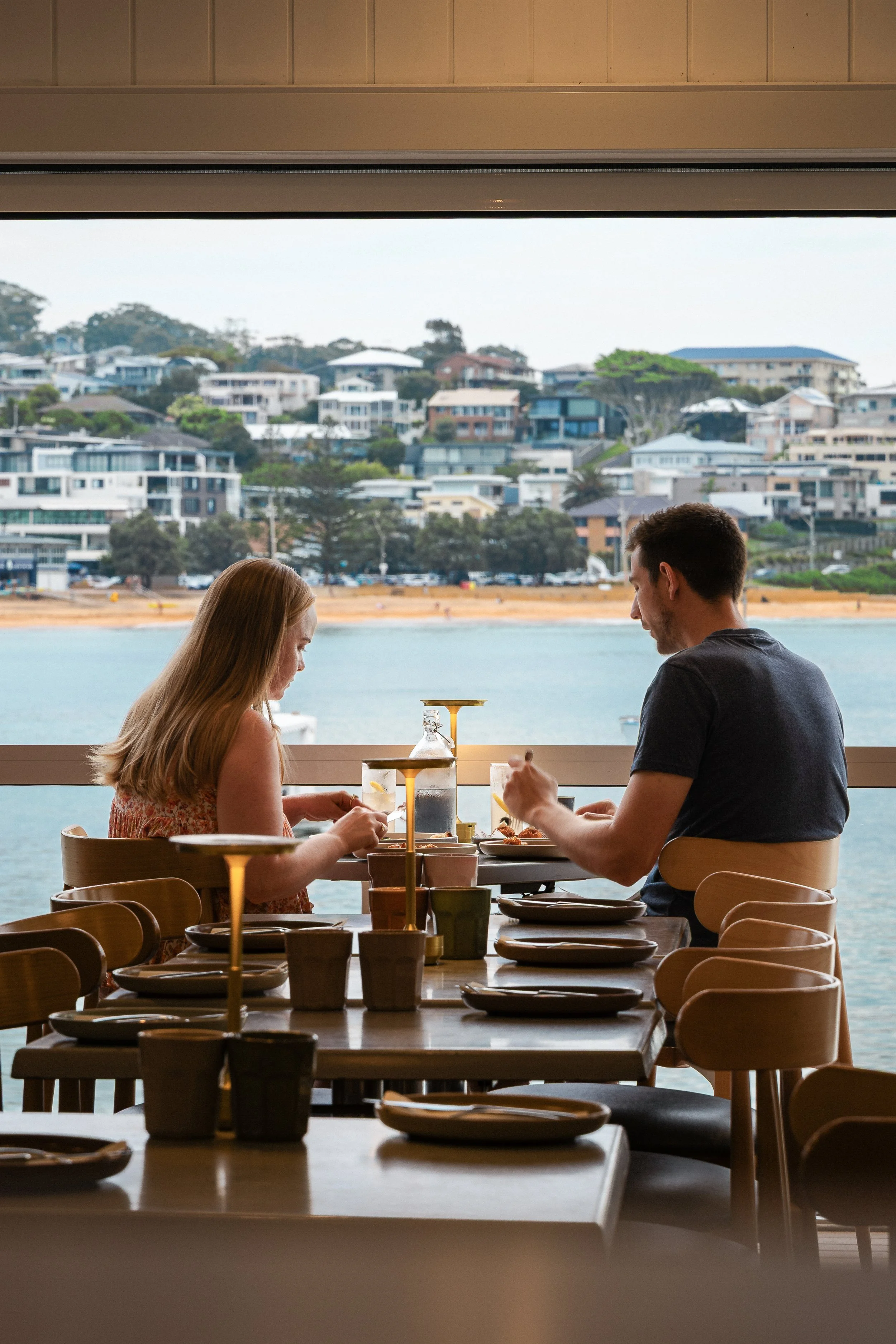 Couple on date night enjoying ambient dining room at Amarilla in Terrigal with waterfront views and tables set for dinner
