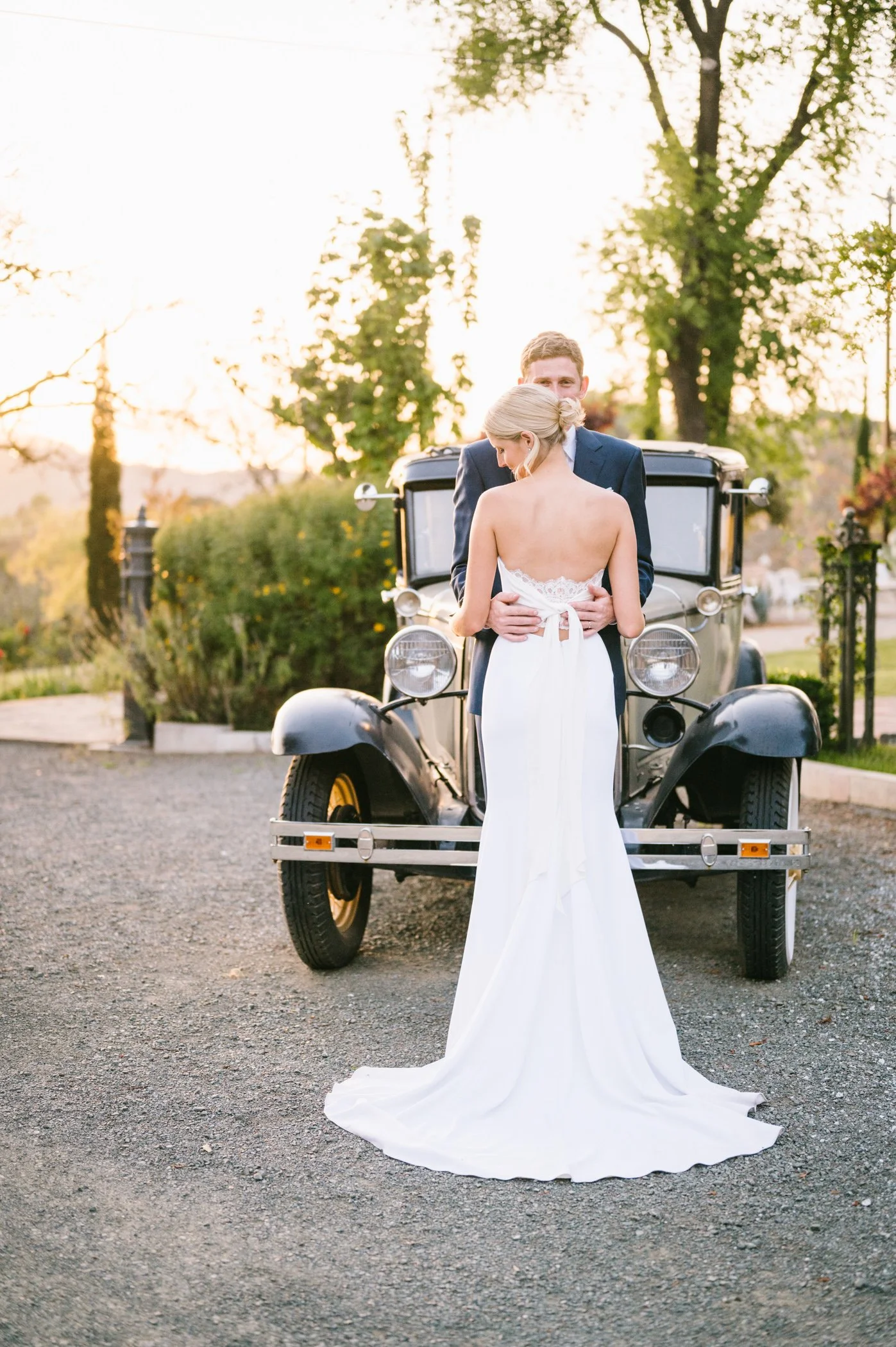 3. Bride and groom in wedding attire standing in front of a vintage car at sunset at Triple S Ranch Napa.