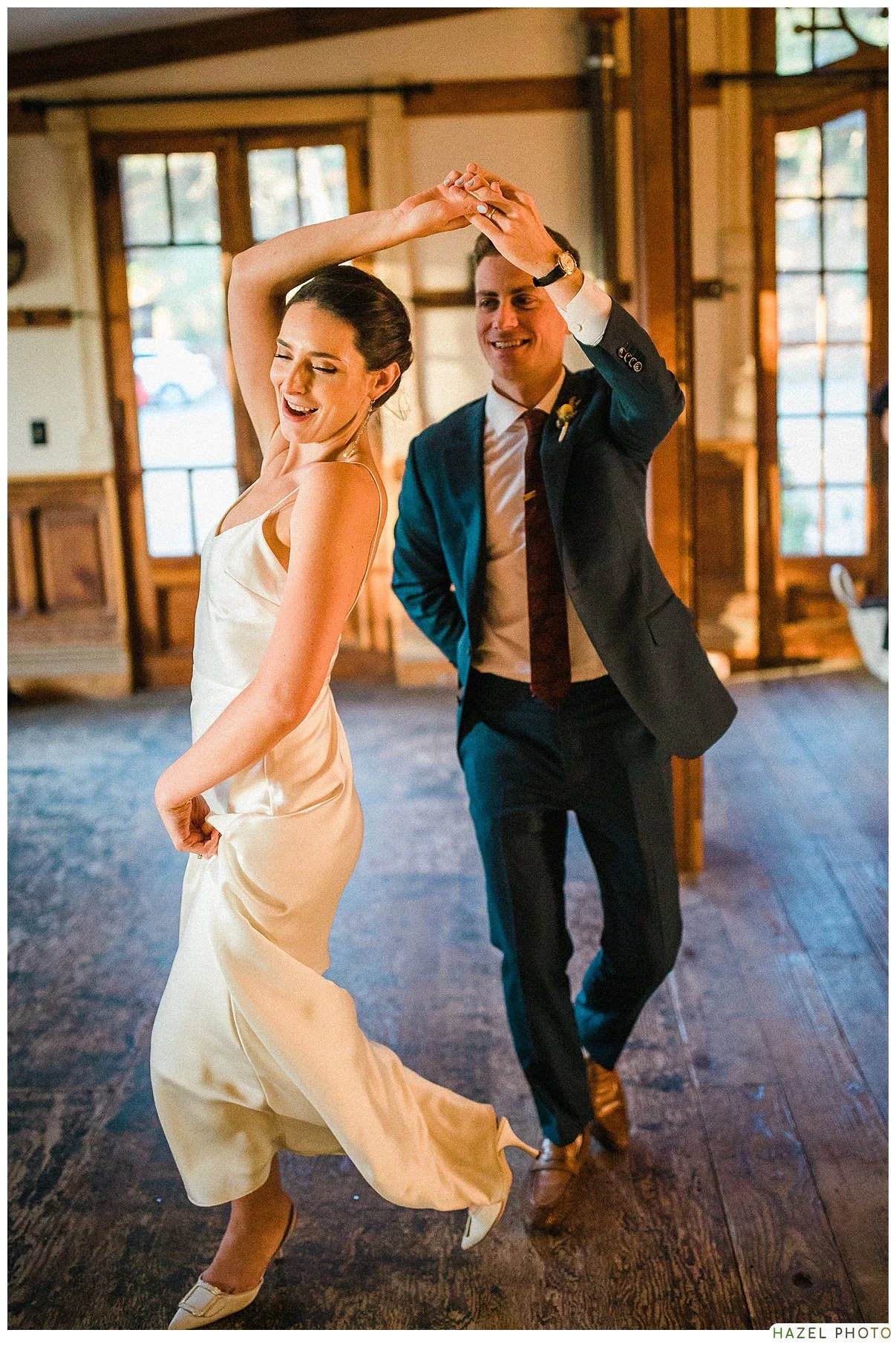 Couple dancing in a wooden room with natural light, smiling and enjoying the moment.