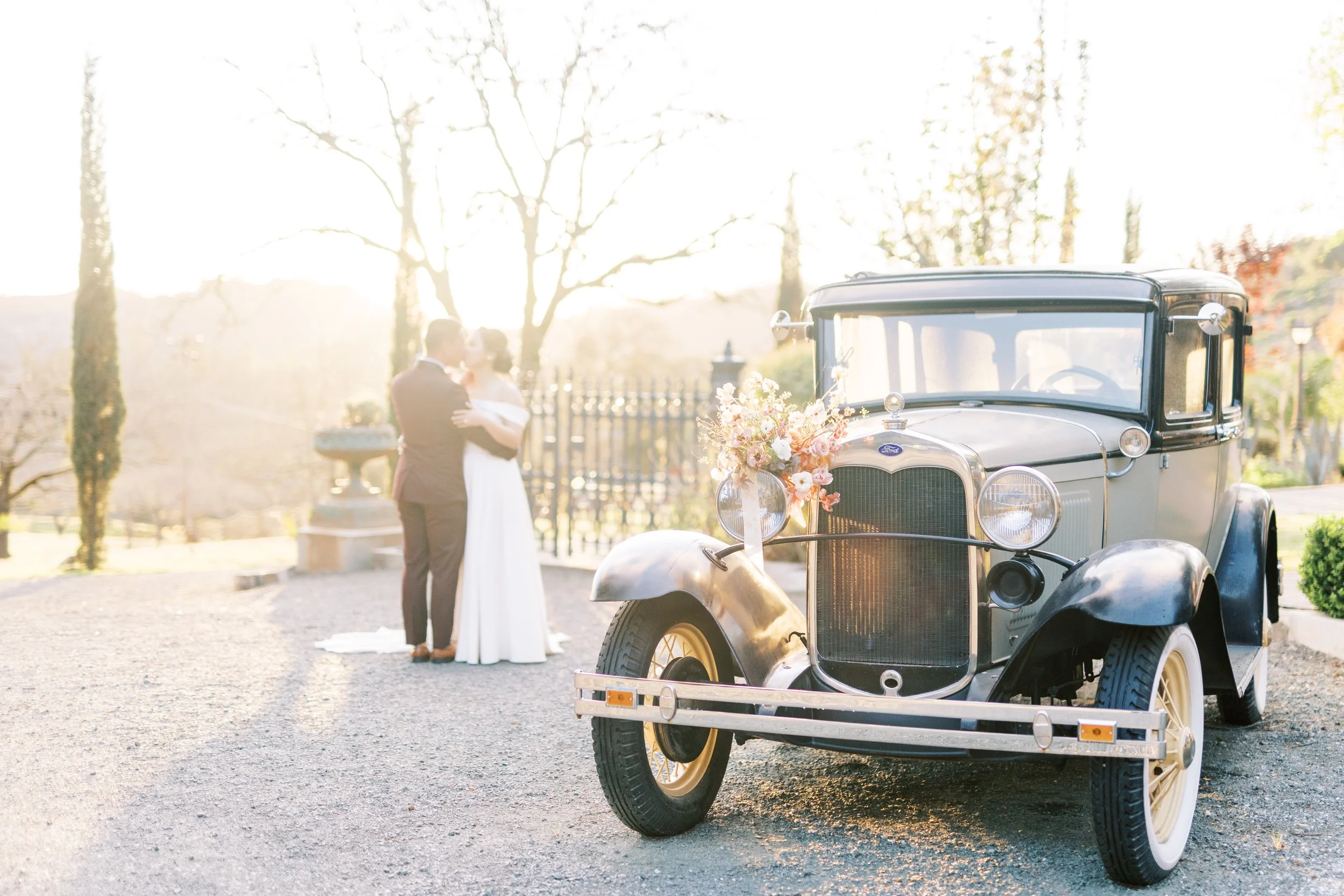 Bride and groom kissing next to vintage Ford car at Triple S Ranch, in Calistoga, California