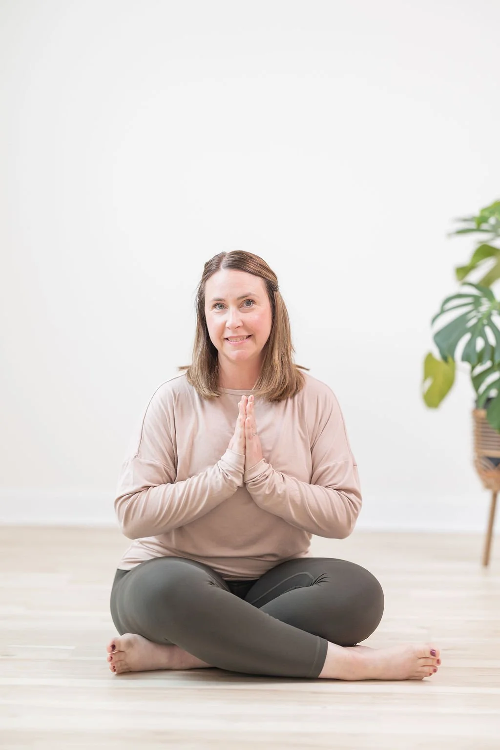 a woman sitting cross legged in prayer hands leading a yoga class