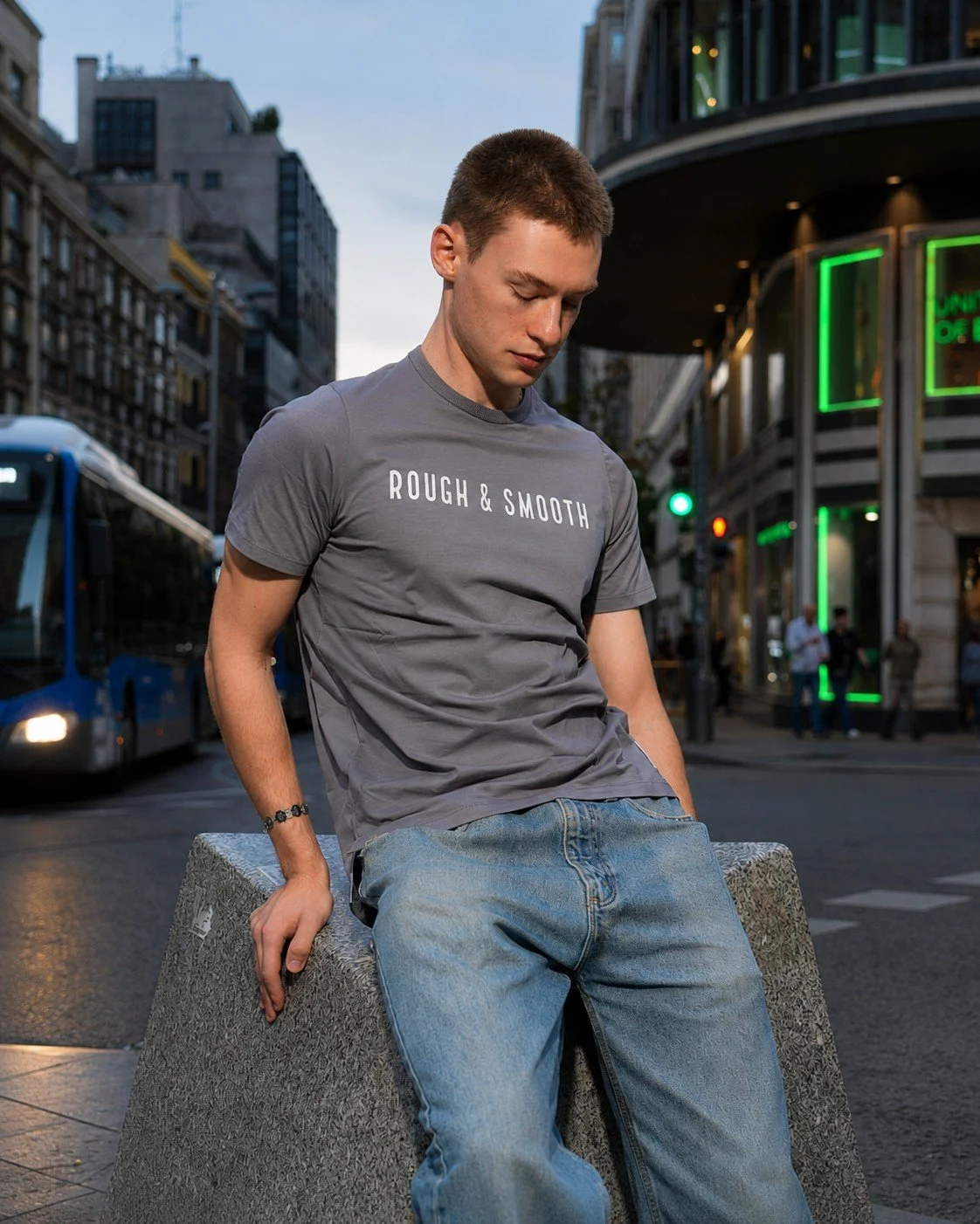 Male model wearing a Rough & Smooth charcoal tee in an urban streetwear setting.
