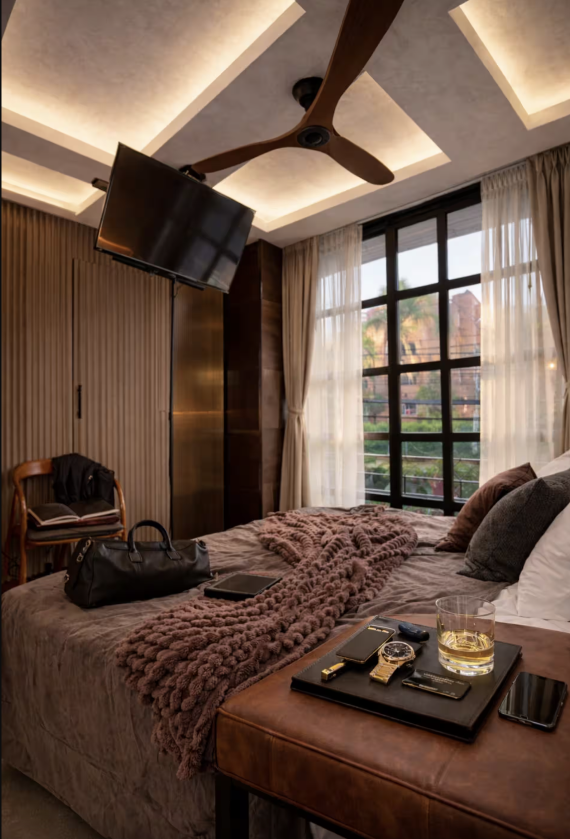 Modern bedroom with neatly arranged pillows on a bed, two bedside tables, a hanging lamp on the left, and a table lamp on the right.