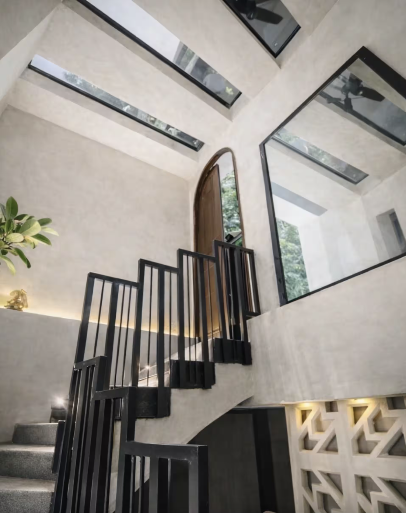Modern bathroom with a marble sink, illuminated mirror, and wooden shelving. Adjacent room visible with stone wall and wooden floors.