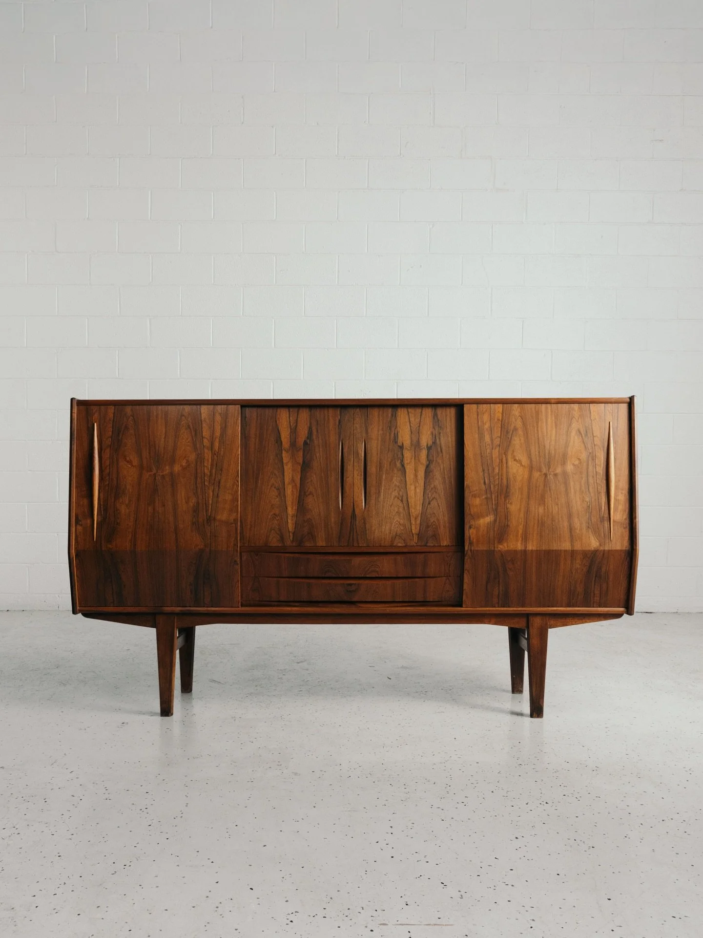 New Arrival from Denmark: This sideboard in rosewood by EW Bach, circa 1960s.

This spectacular piece features ideal proportions, an elegant angular frontage, and stunning rosewood grain.

Equipped with two sliding doors, revealing storage beneath wi