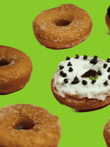 Variety of donuts on a green background, one with white icing and chocolate chips.
