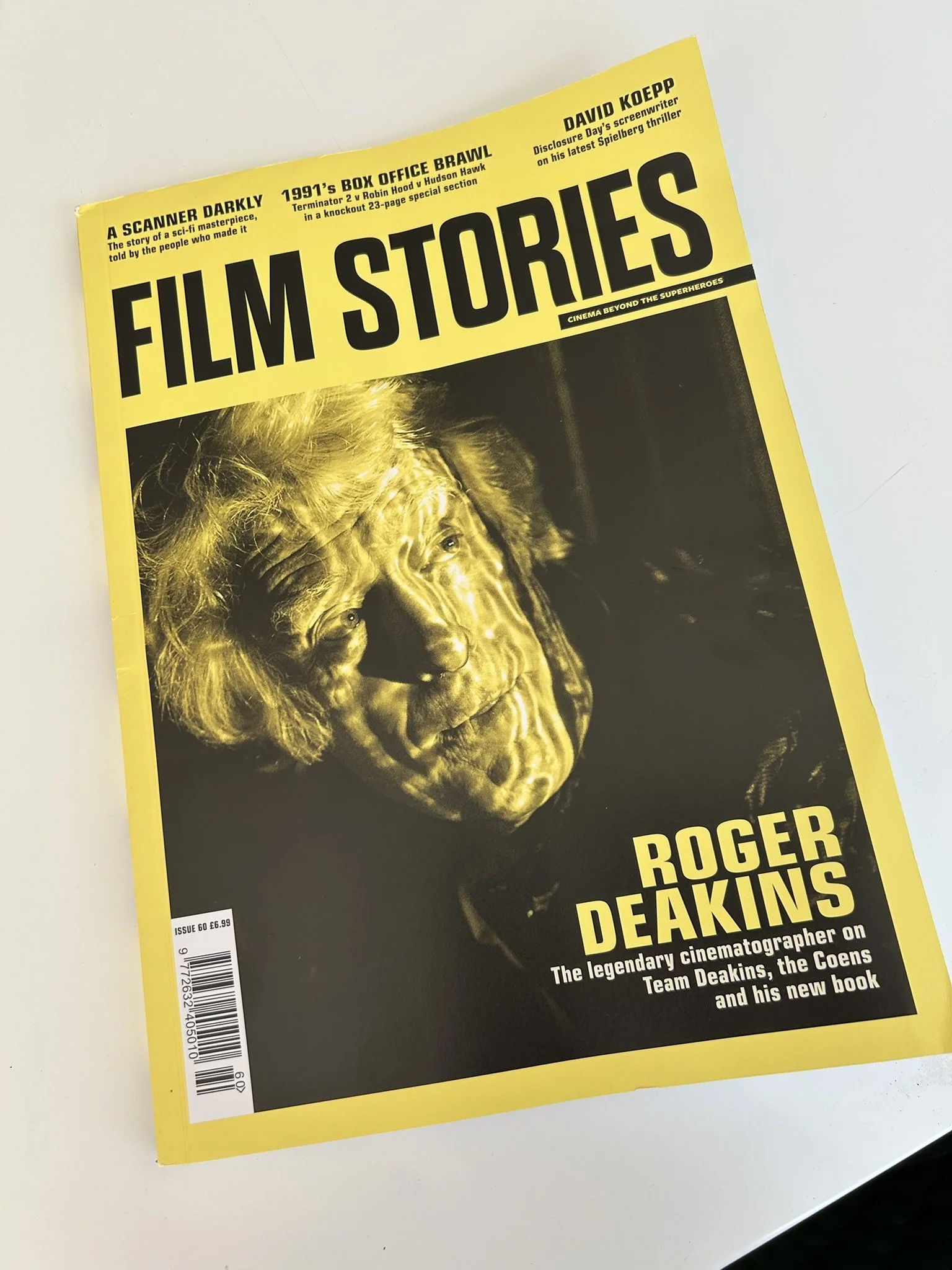 The cover of a magazine titled 'Film Stories' with a yellow border. The cover features a black and white image of Roger Deakins, with text highlighting articles about Roger Deakins, a cinematographer, and other film industry topics.