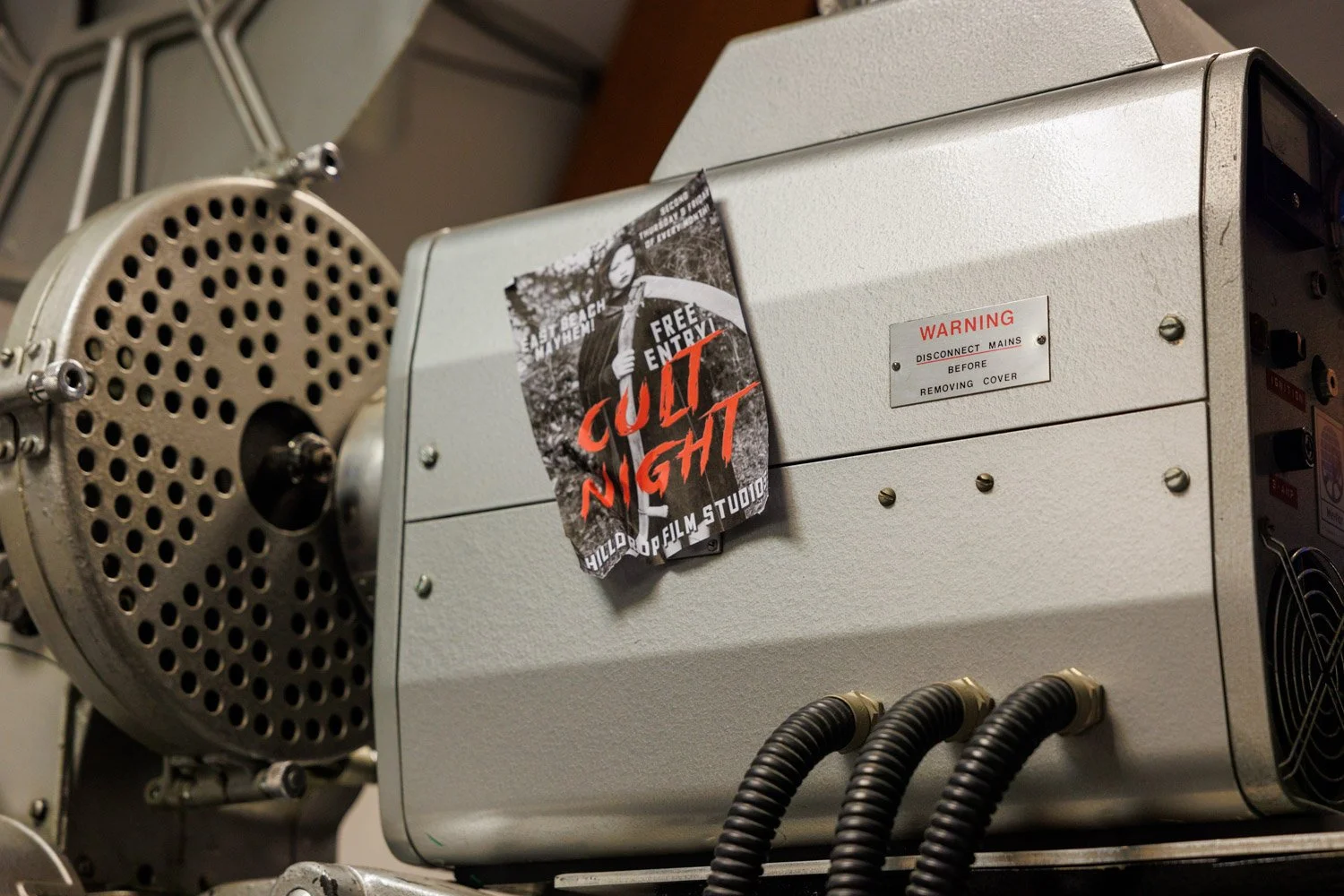 Part of a film projector with a poster reading "Cult Night" attached to it.