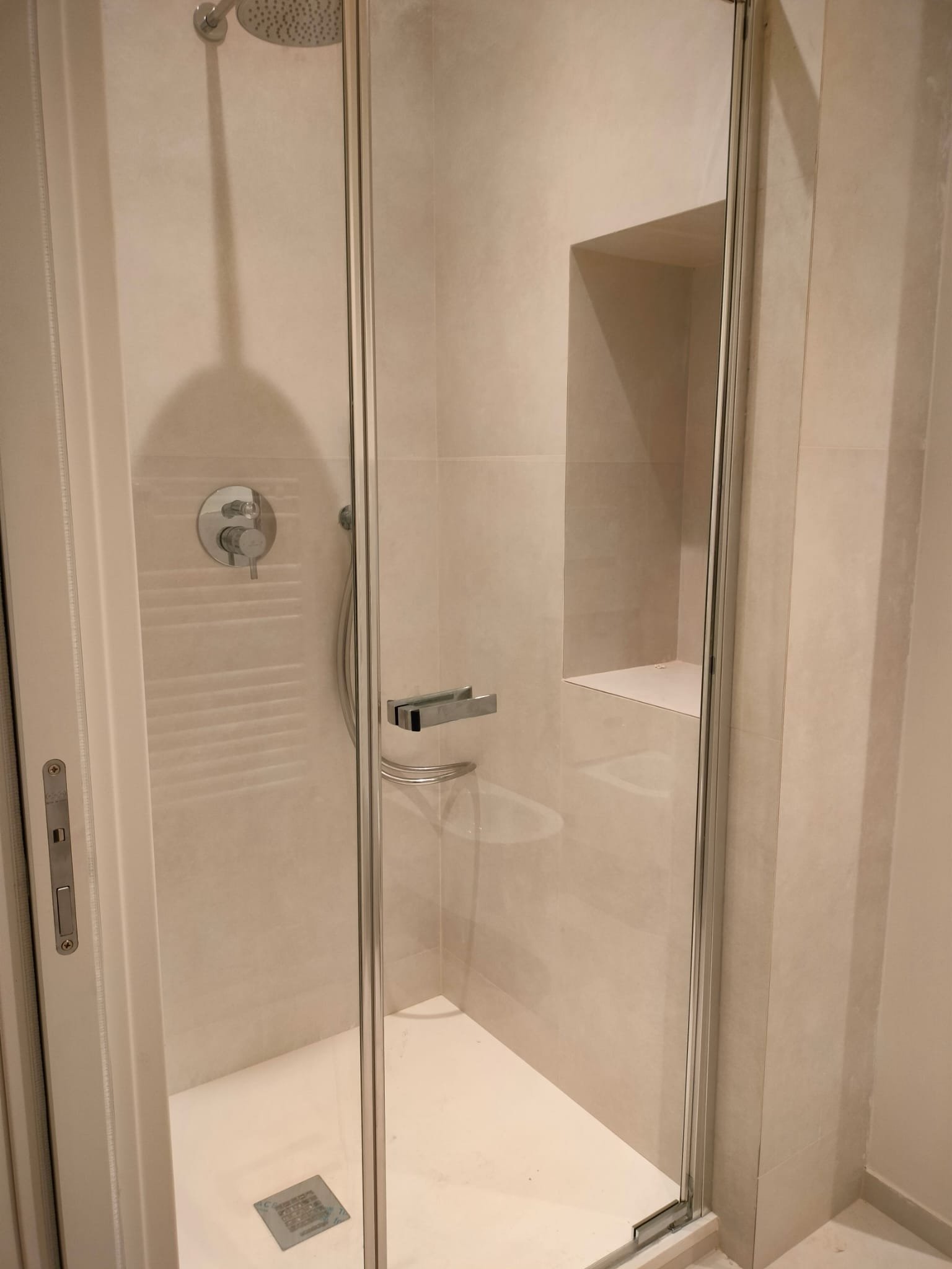 Una doccia con pareti in vetro, una manopola per il controllo dell'acqua e una doccia a pioggia.