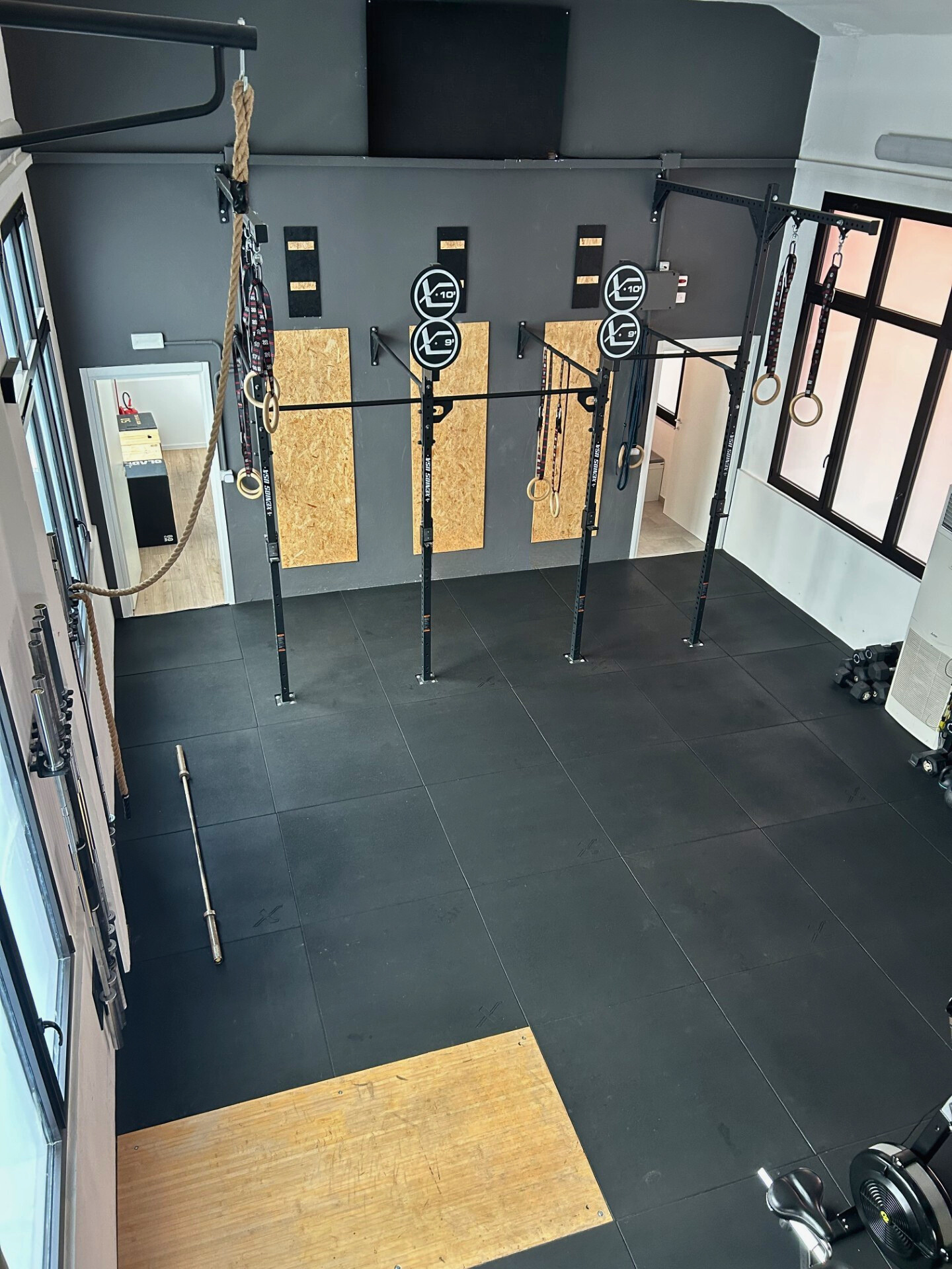 Sala di allenamento con attrezzature per trazioni e esercizi a corpo libero, in particolare anelli, barra orizzontale, e corda da arrampicata.