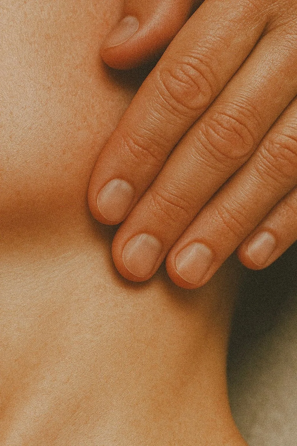 Close-up of a person's hand with fingers gently pressing on their neck.