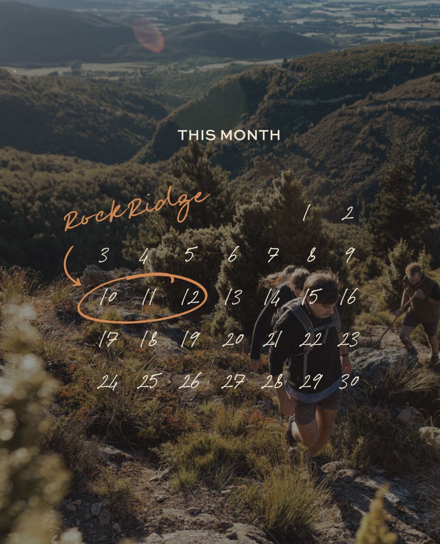 RockRidge Hikers on a rocky trail in a mountainous landscape. Overlaid with text and numbers marking the dates of the month, with 'This Month' at the top and 'RockRidge' written in cursive, with an arrow pointing to the numbers 10 to 12.