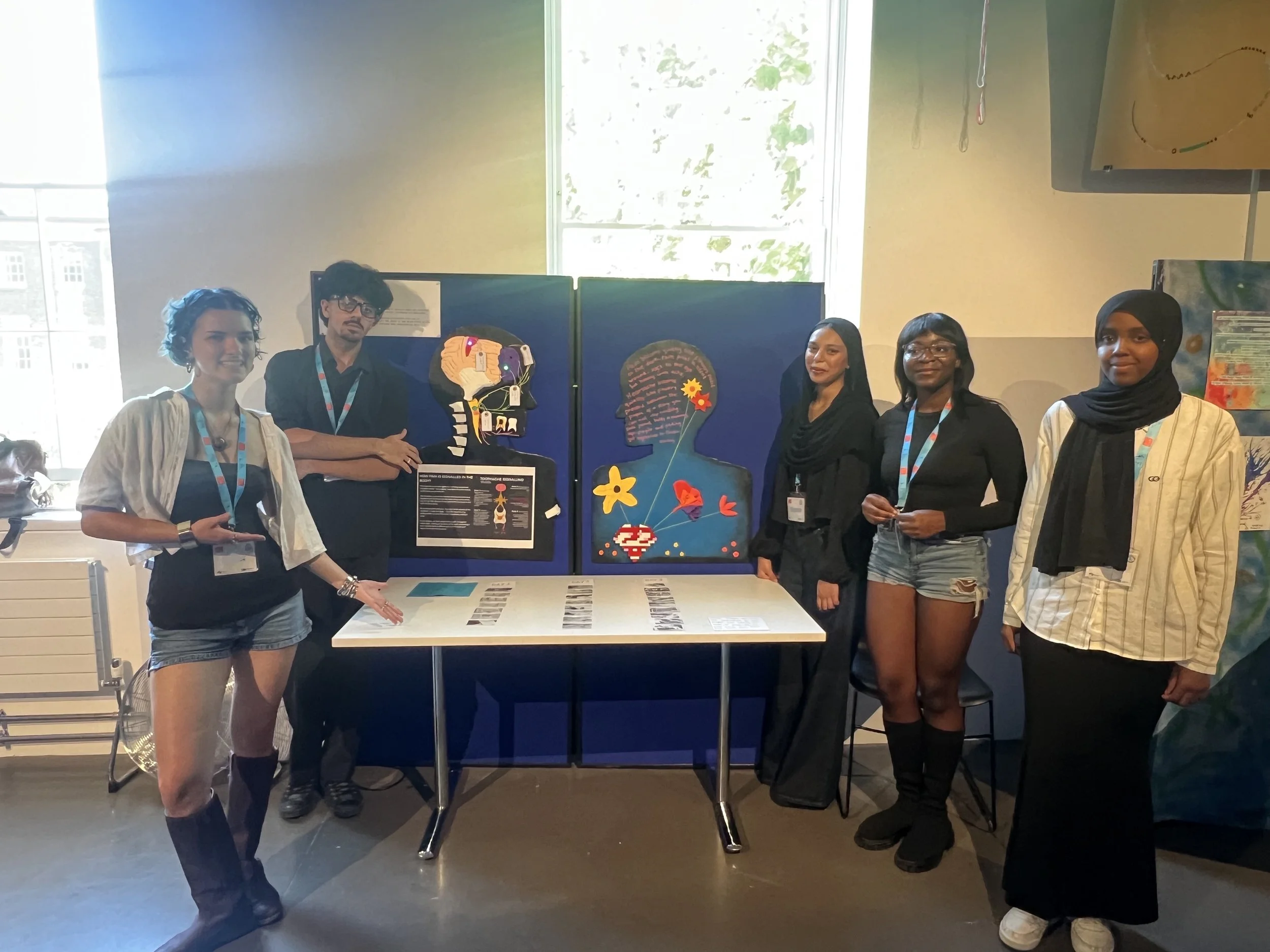 The Pain Blooms group stand around their display smiling and gesturing to it.