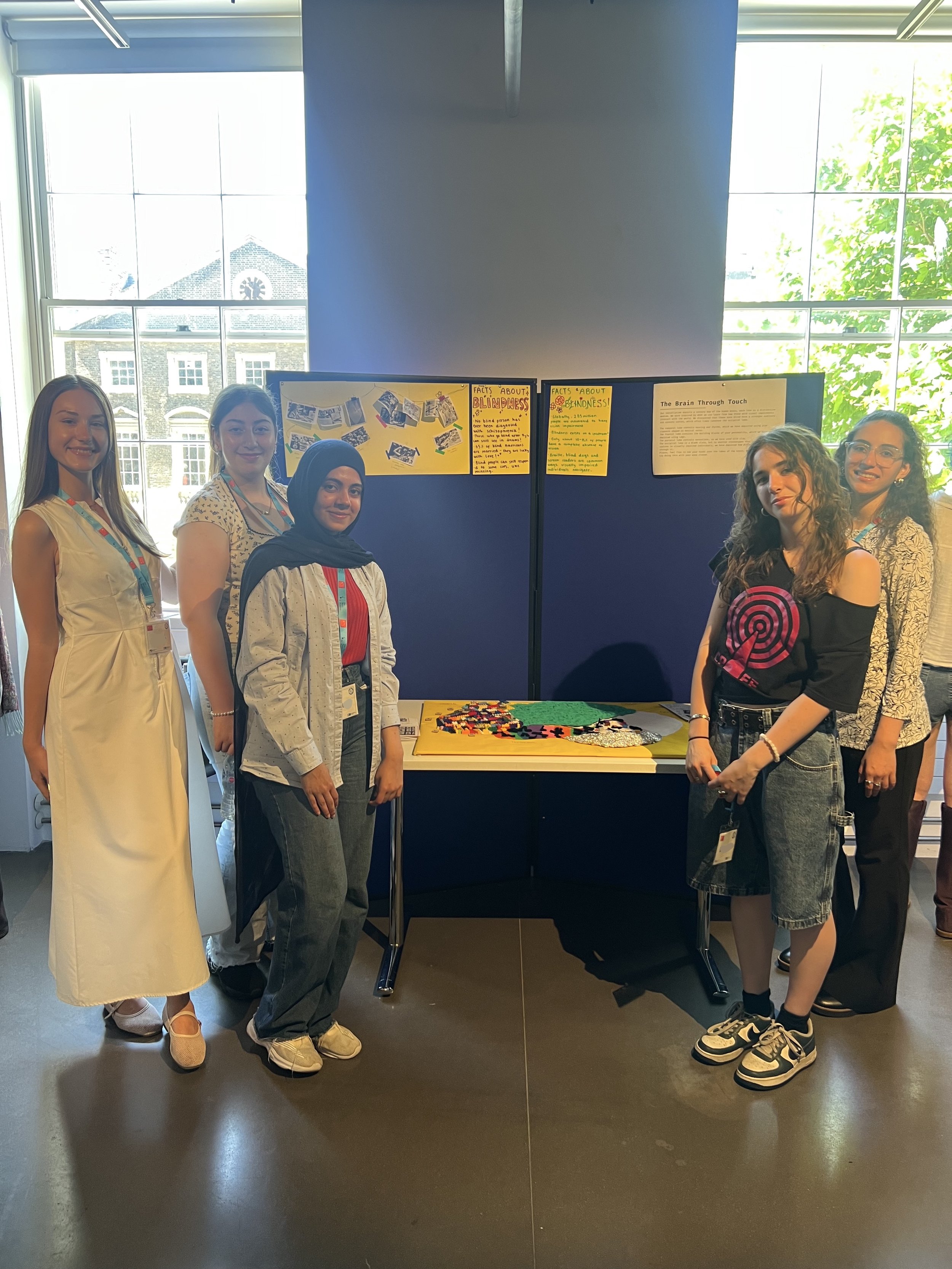 The Brain through Touch group stand around their group project smiling.