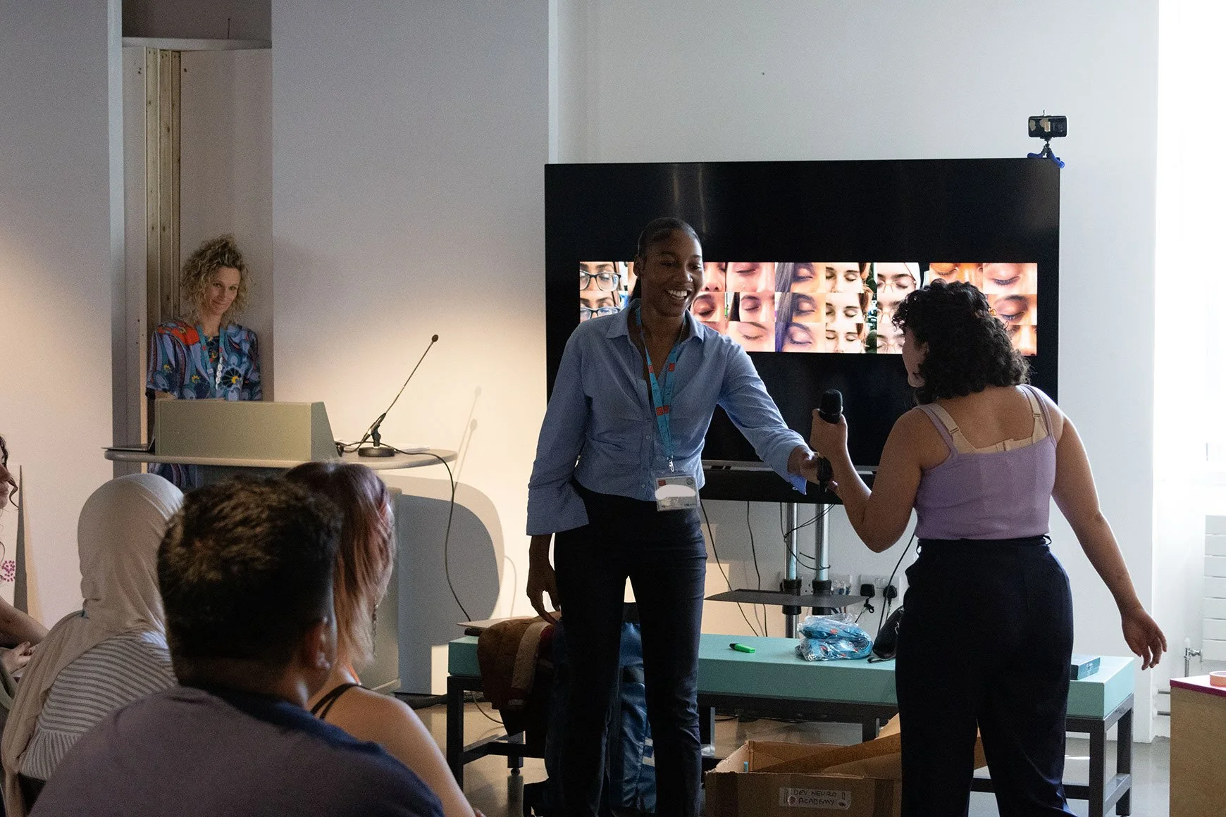 Two DNA CREATE participants pass the mic as they present their project.