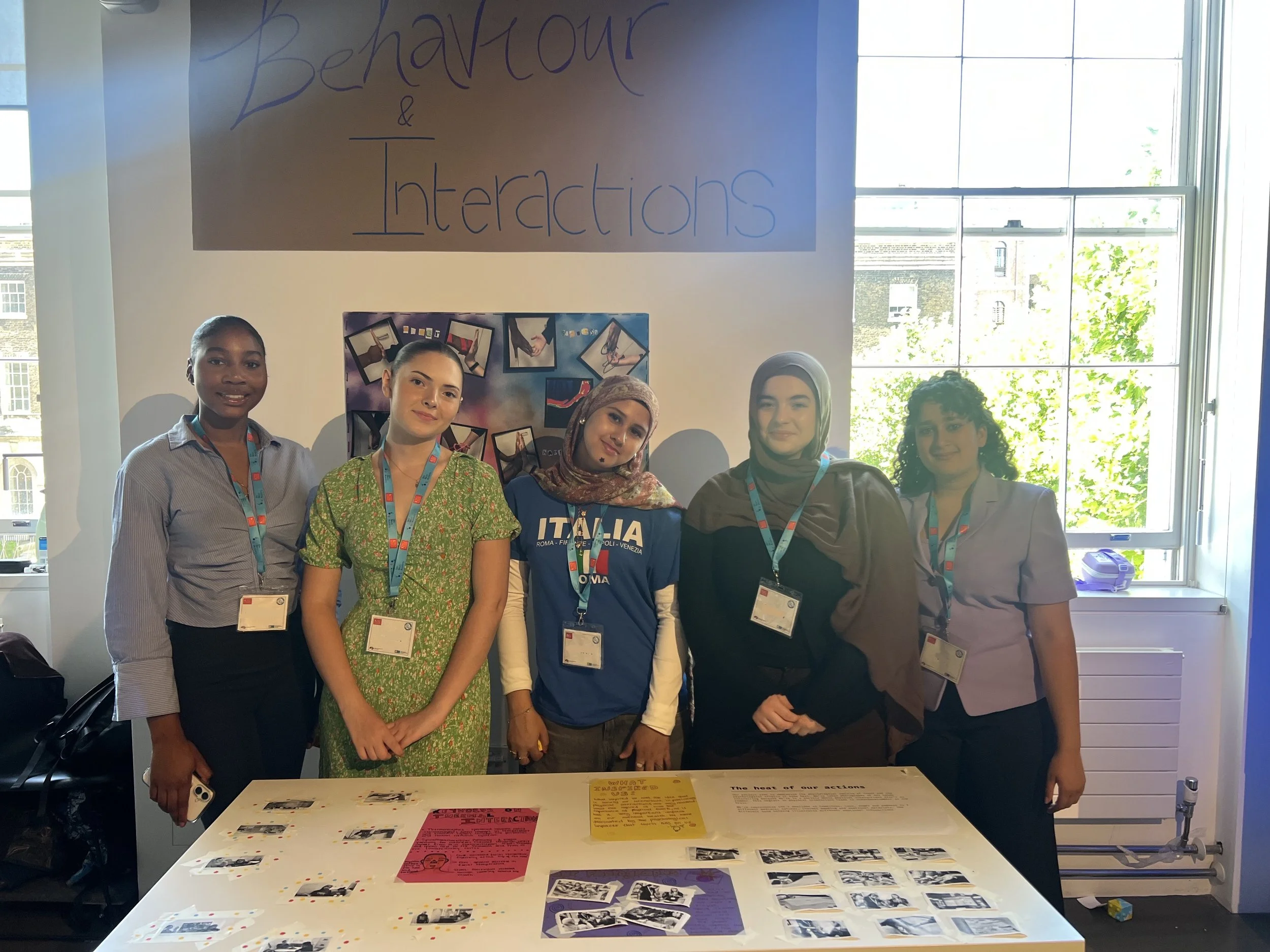 The Heat of our Actions group standing, smiling behind their group project.
