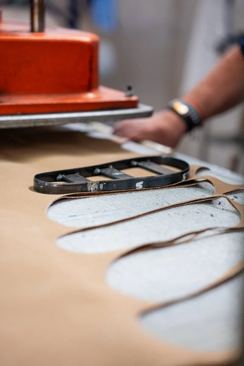 Máquina de corte industrial con troquel y material textil en una superficie de trabajo.
