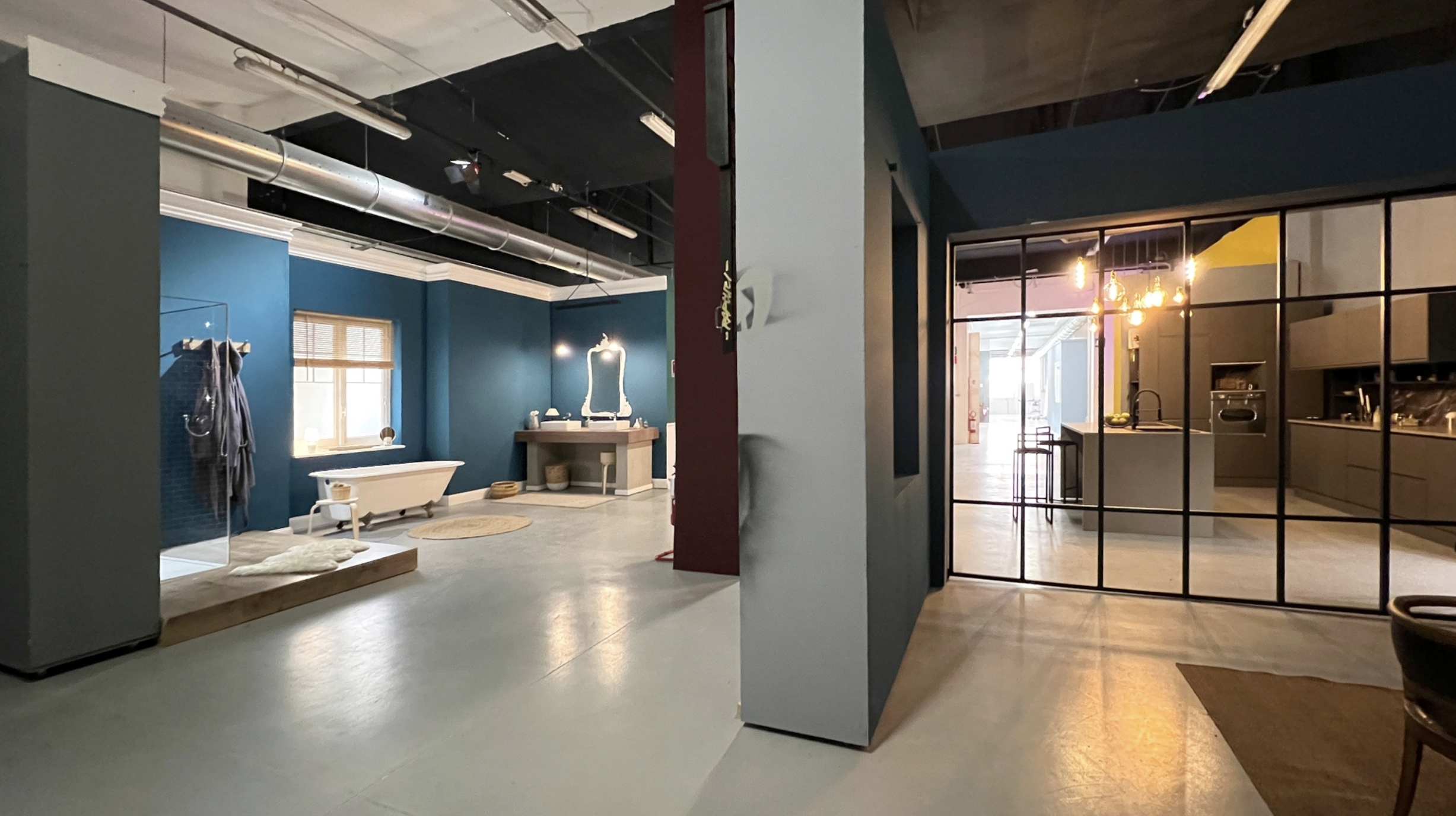 Interni di appartamento moderno con pareti blu, vasca da bagno, lavabo con specchio, cucina con illuminazione calda, pareti divisorie in vetro.
