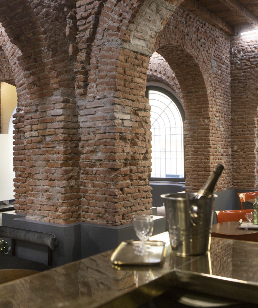 Interno di un ristorante con muri in mattoni a vista e grandi archi.