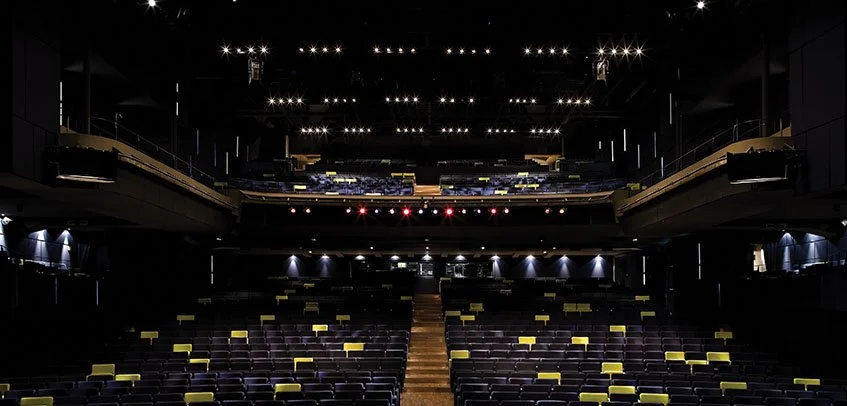 Interno di un teatro vuoto con sedili e un palco in evidenza.