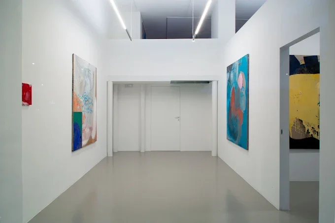Galleria d'arte moderna con pareti bianche e dipinti astratti colorati appesi alle pareti.