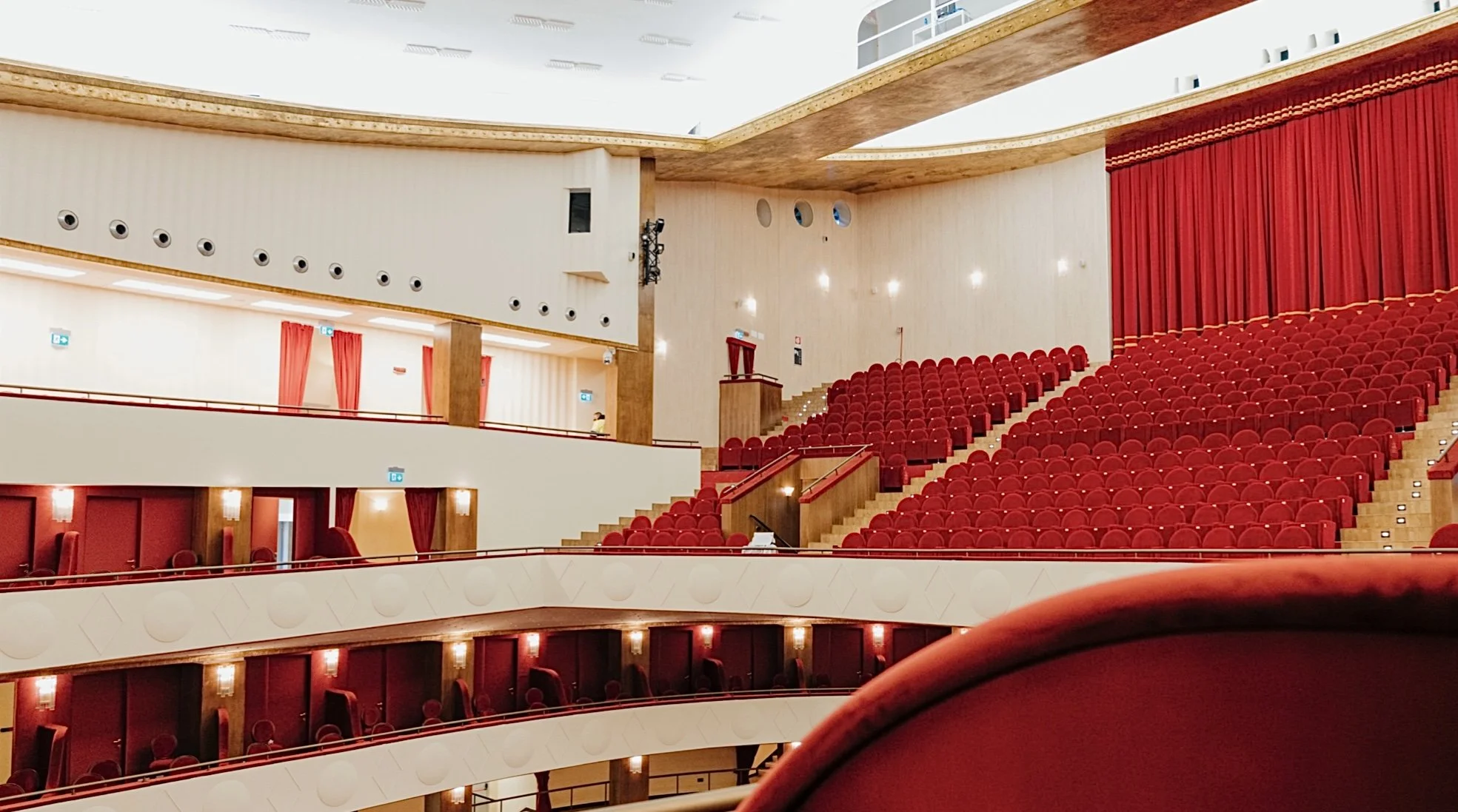Auditorium vuoto con sedili rossi e tende rosse, vista dall'interno.
