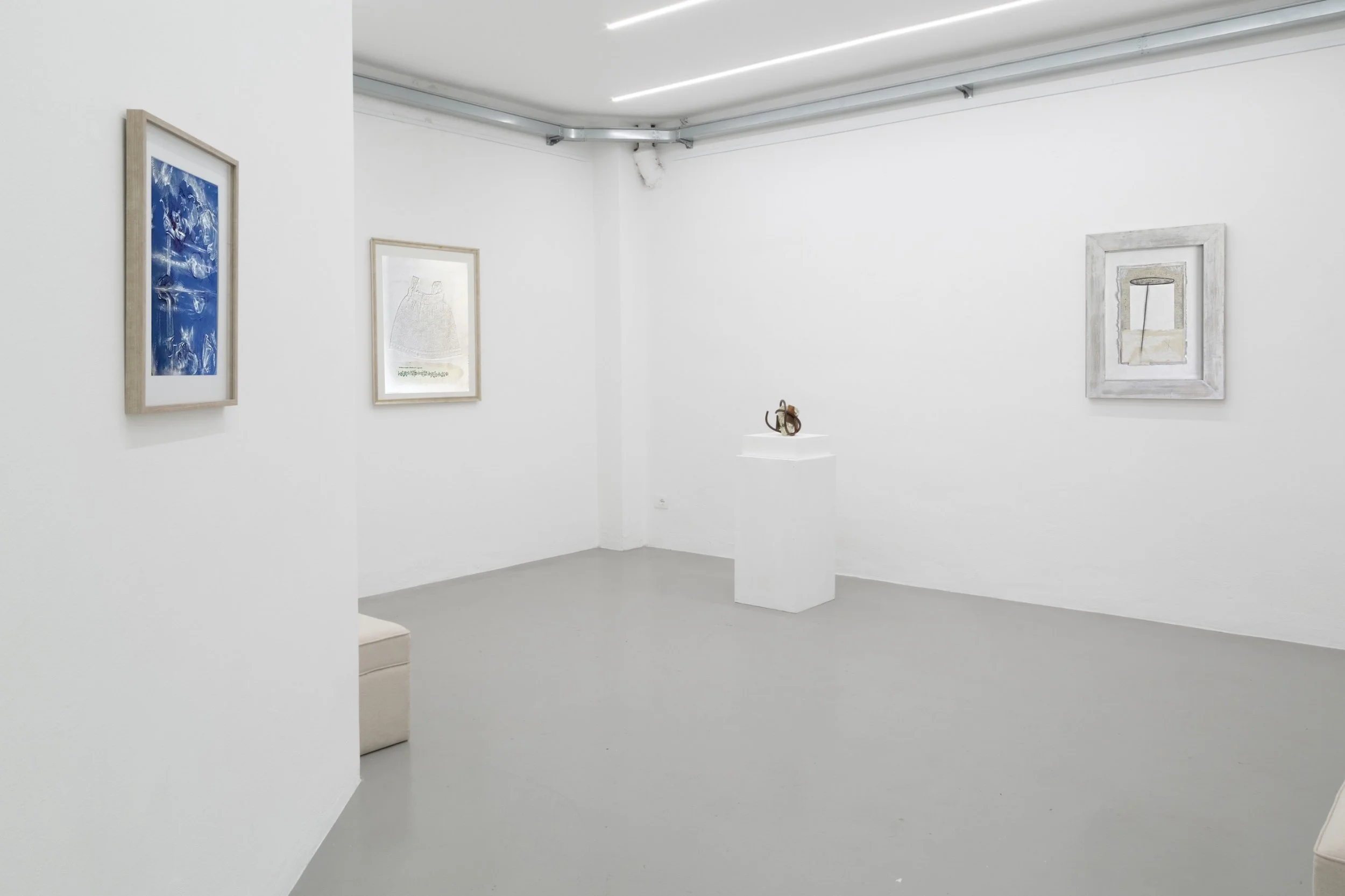 Interno di una galleria d'arte con pareti bianche, quadri e sculture esposte.