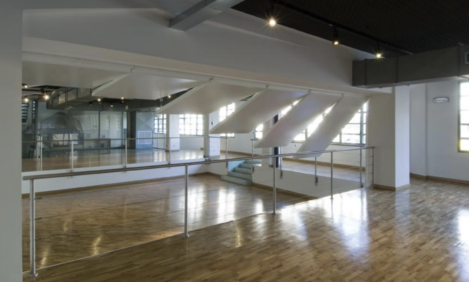 Interno di uno spazio vuoto con pavimento in parquet, grandi finestre e strutture moderne