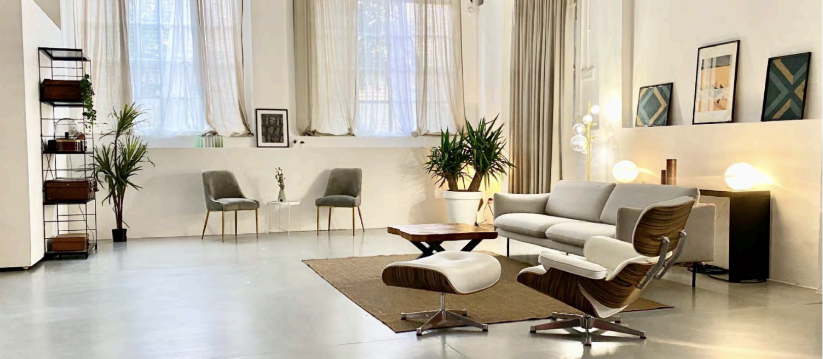 Soggiorno minimalista con sofa, poltrone, tavolino in legno, tappeto, piante, quadri e lampade