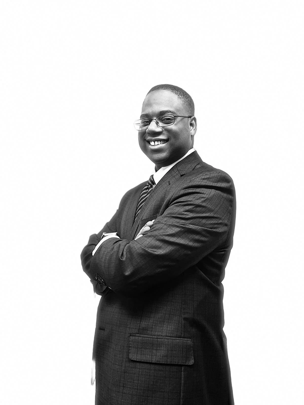 Portrait of a smiling man in a suit with glasses, arms crossed.