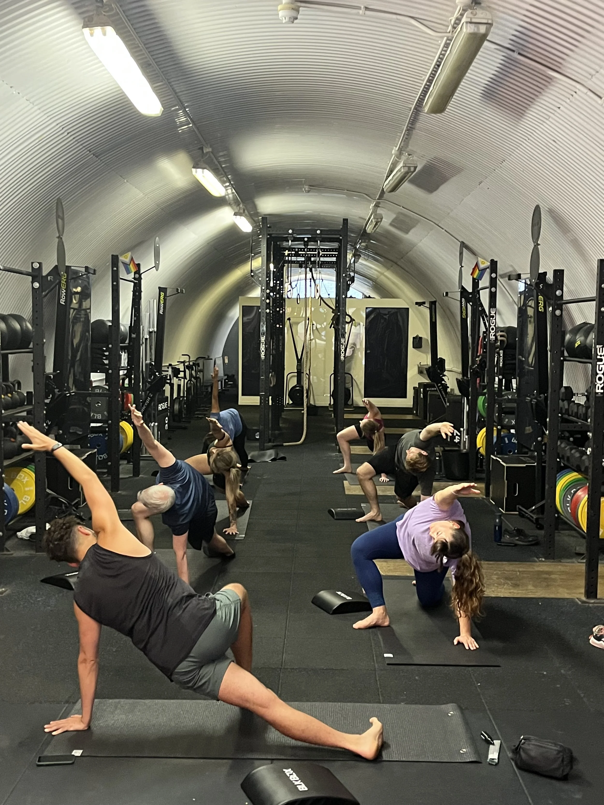 People practicing yoga in a gym inside a tunnel-like structure.