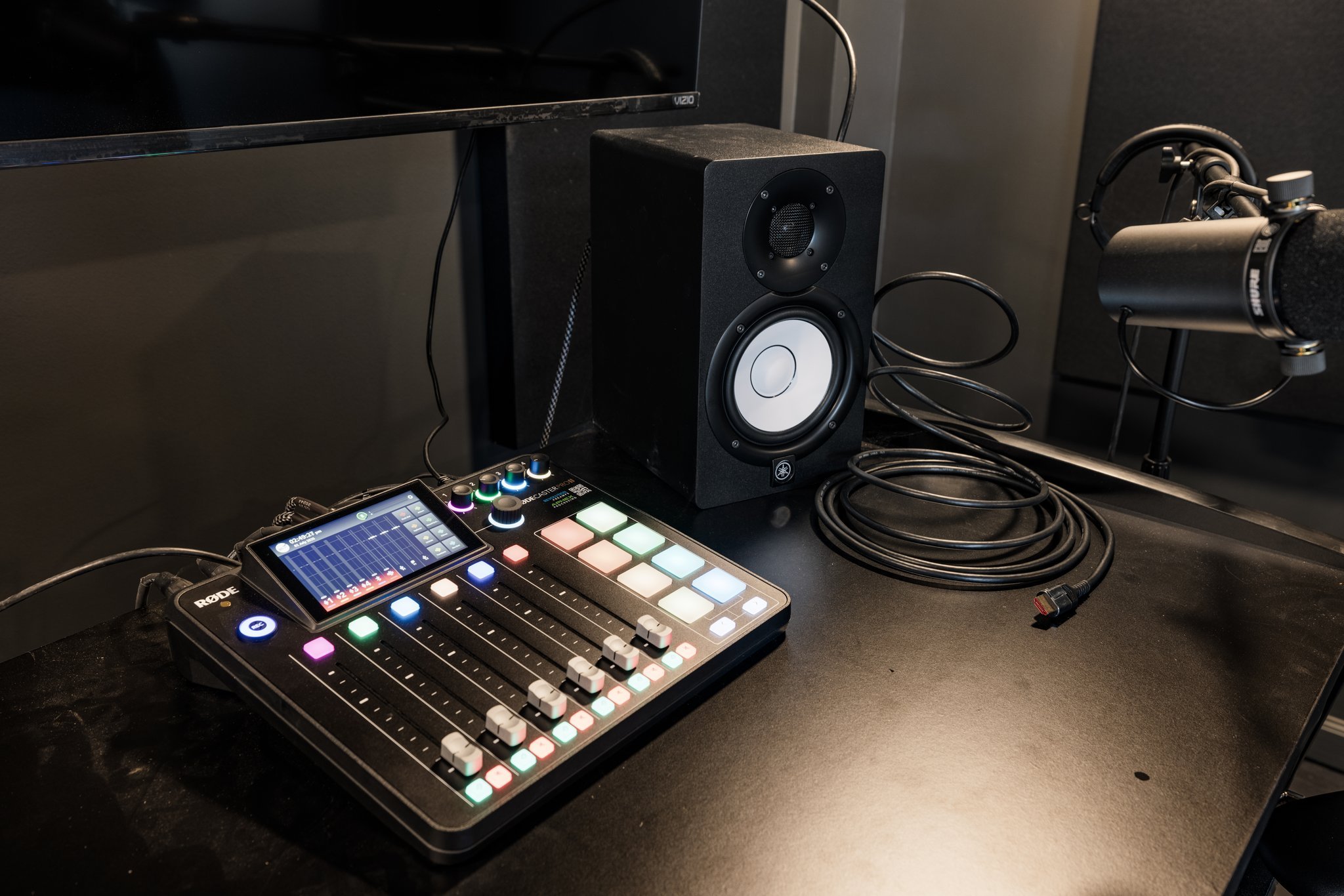 Audio mixing console with colorful buttons, a speaker, a microphone, and a monitor on a black surface.