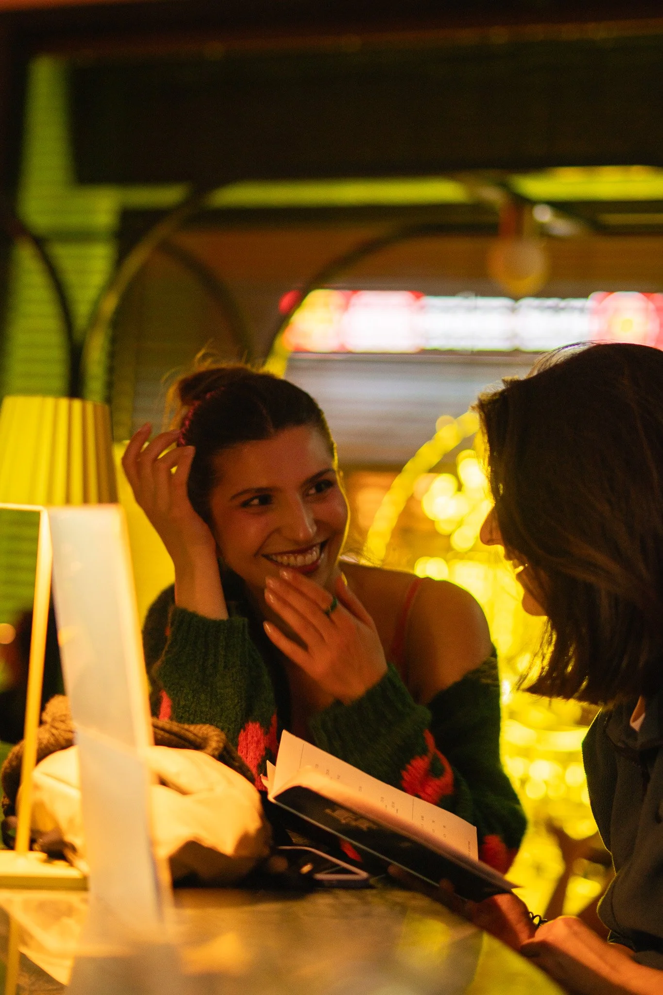 Zwei Frauen sprechen in einem Café bei warmem Licht.