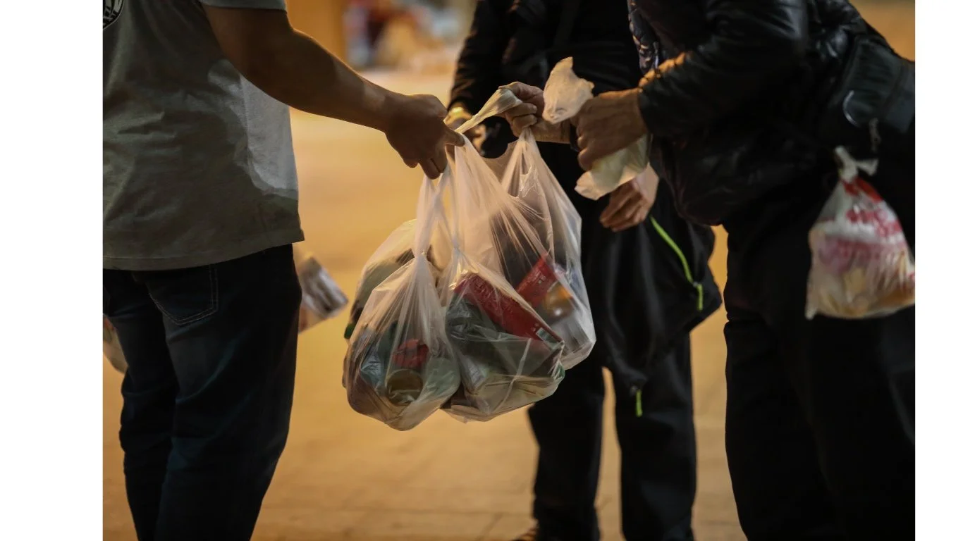 People exchanging plastic bags filled with canned goods and items.