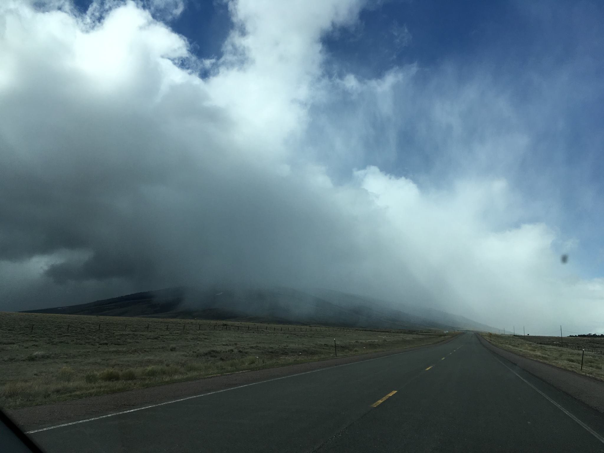 A cloud with snow moving across the ground in the mountains