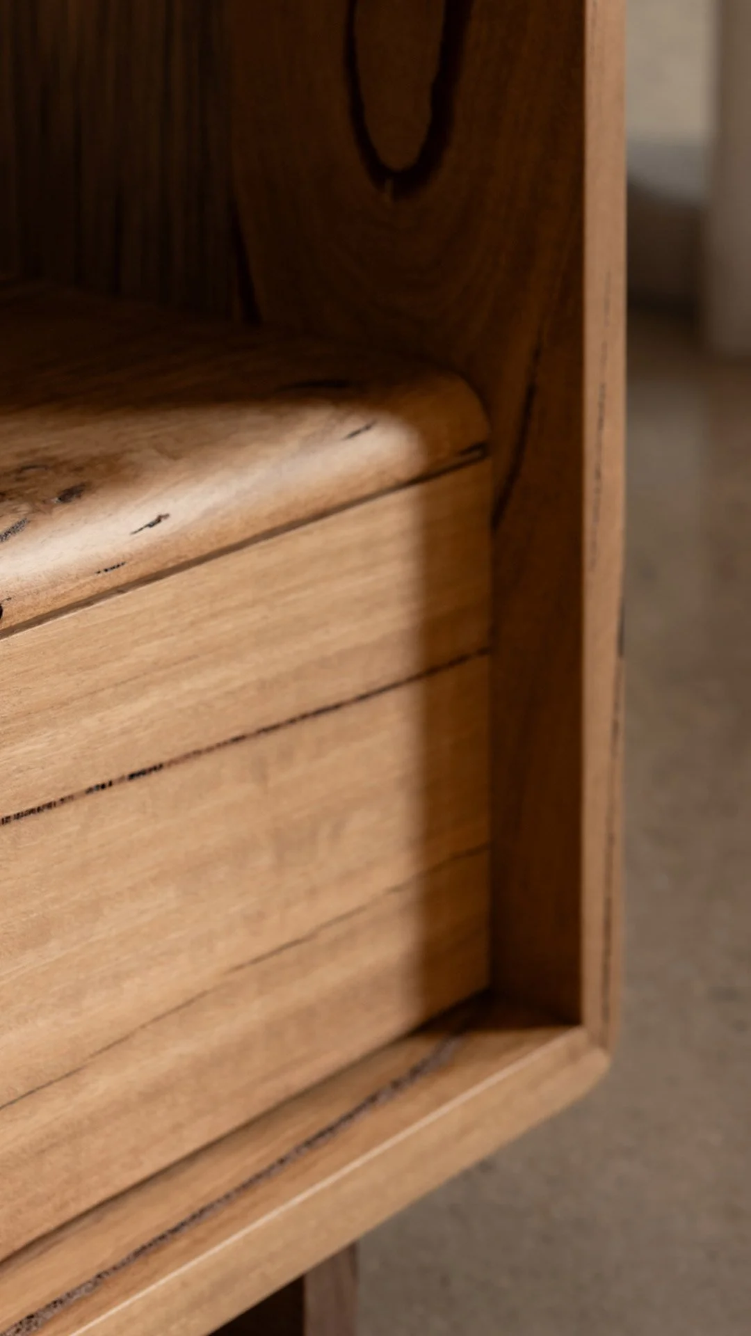 Close-up of a corner of a wooden piece of furniture, showing the wood grain and smooth finish.