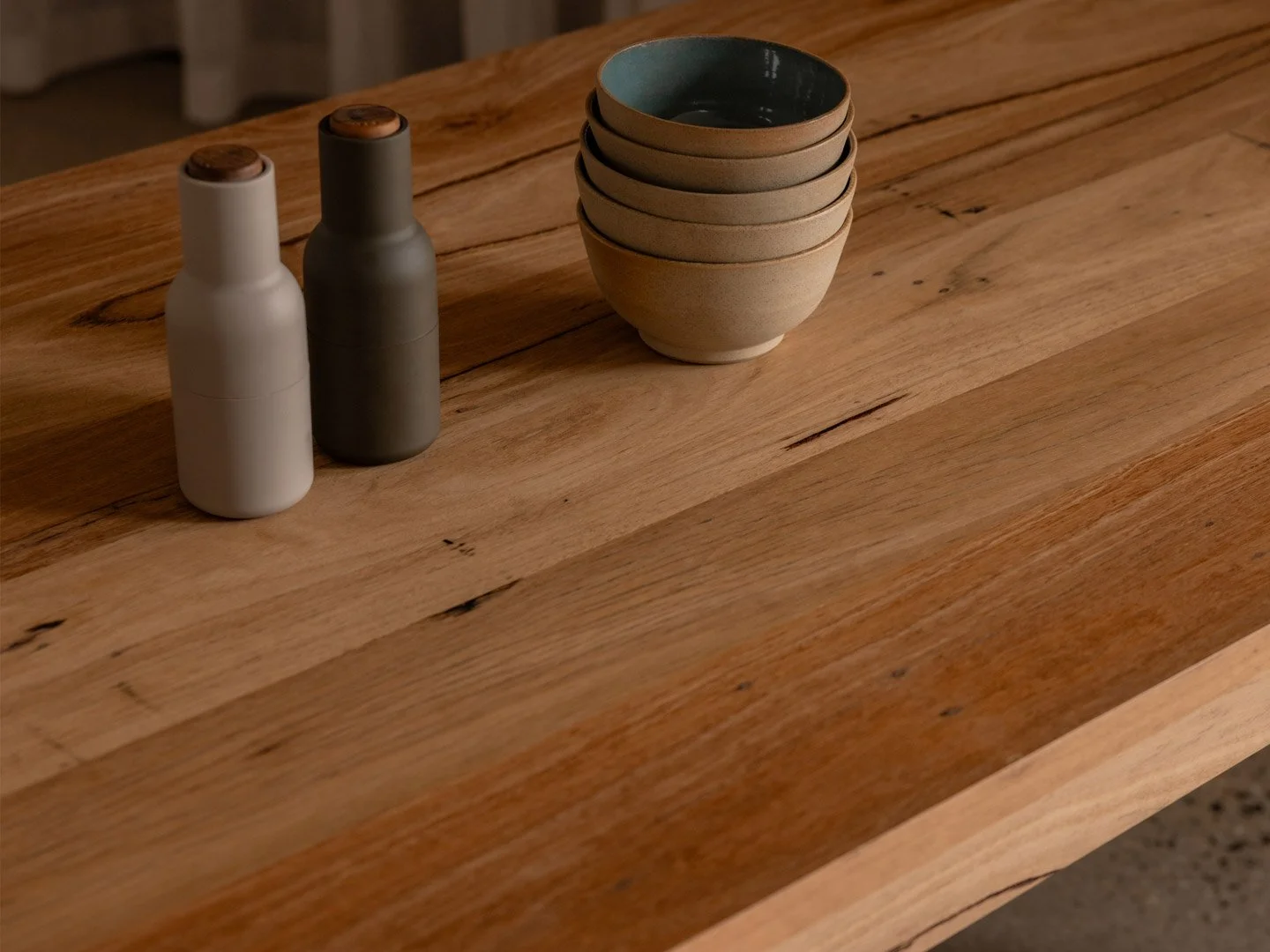 A wooden table with two ceramic bottles and a stack of five ceramic bowls.