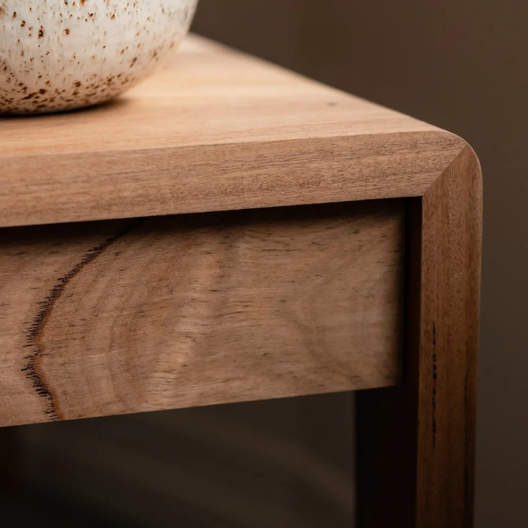 Close-up of a wooden table corner with specialist joinery and a partial ceramic object.