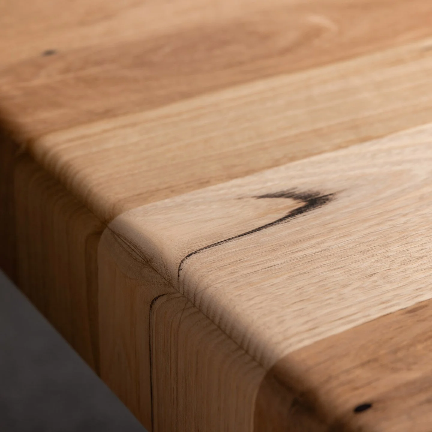 Close-up of a reclaimed timber surface with a crack and dark streak along the grain.