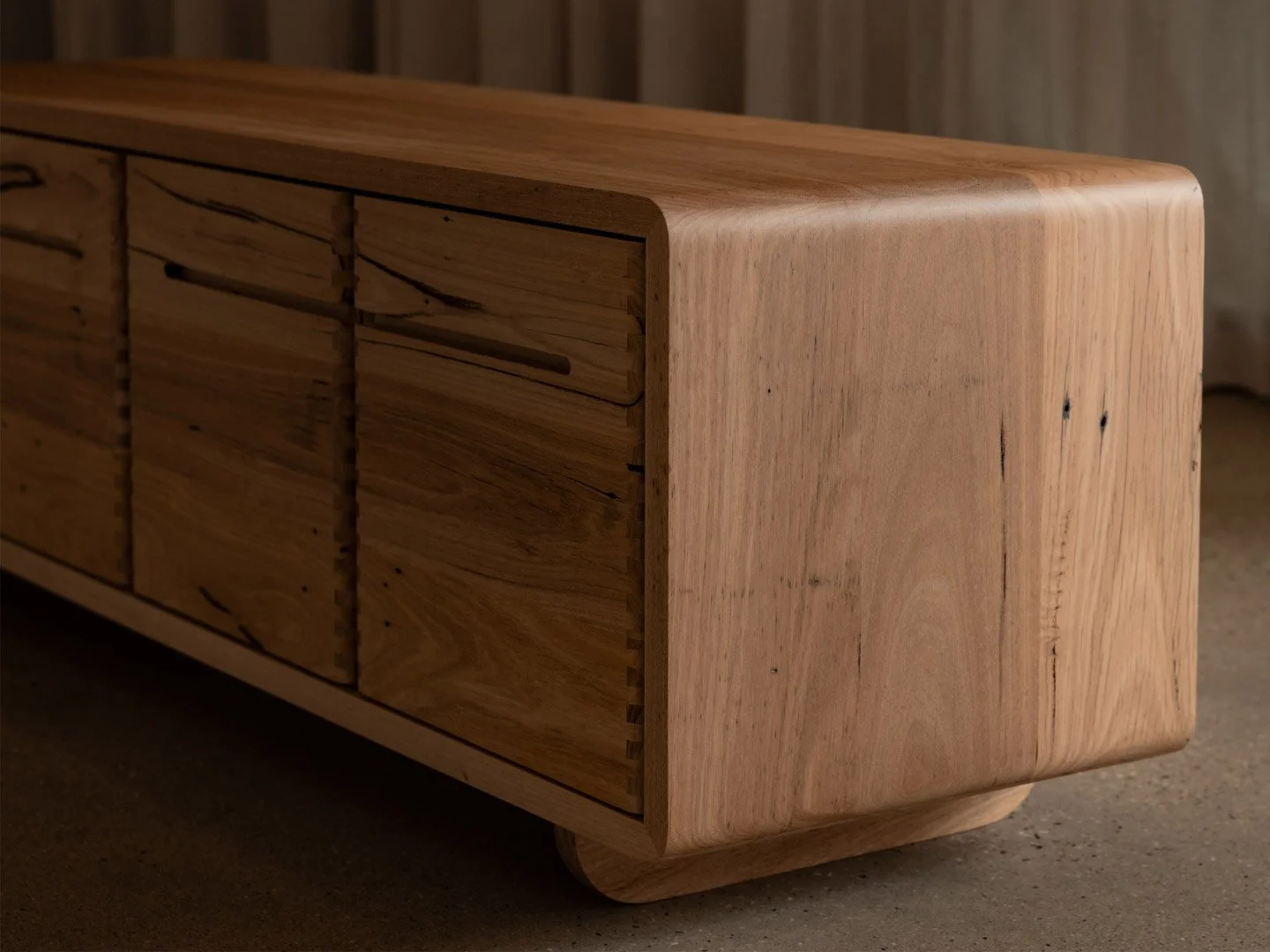 Close-up of a wooden furniture piece with smooth, rounded edges and a natural finish, showcasing the wood grain and joints.