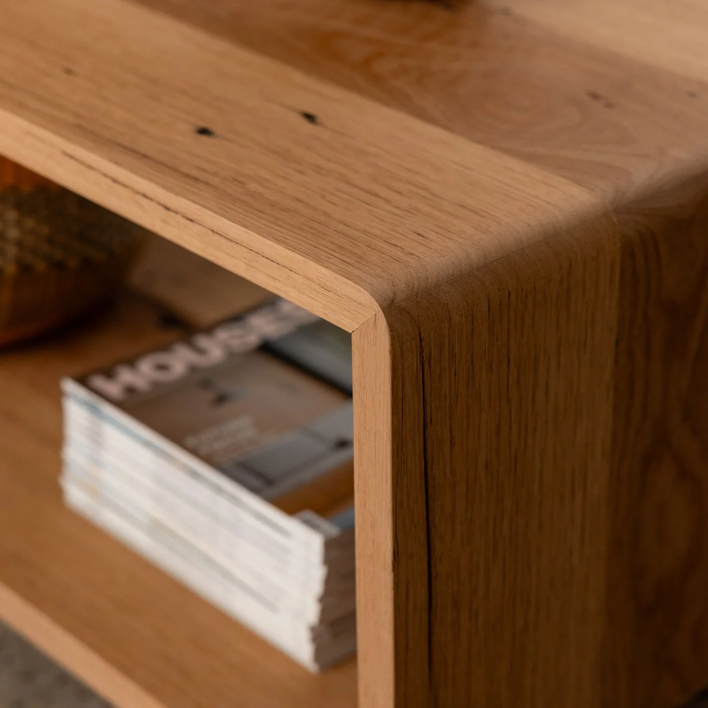 Close-up of a wooden bookshelf with magazines or catalogs inside a lower compartment.