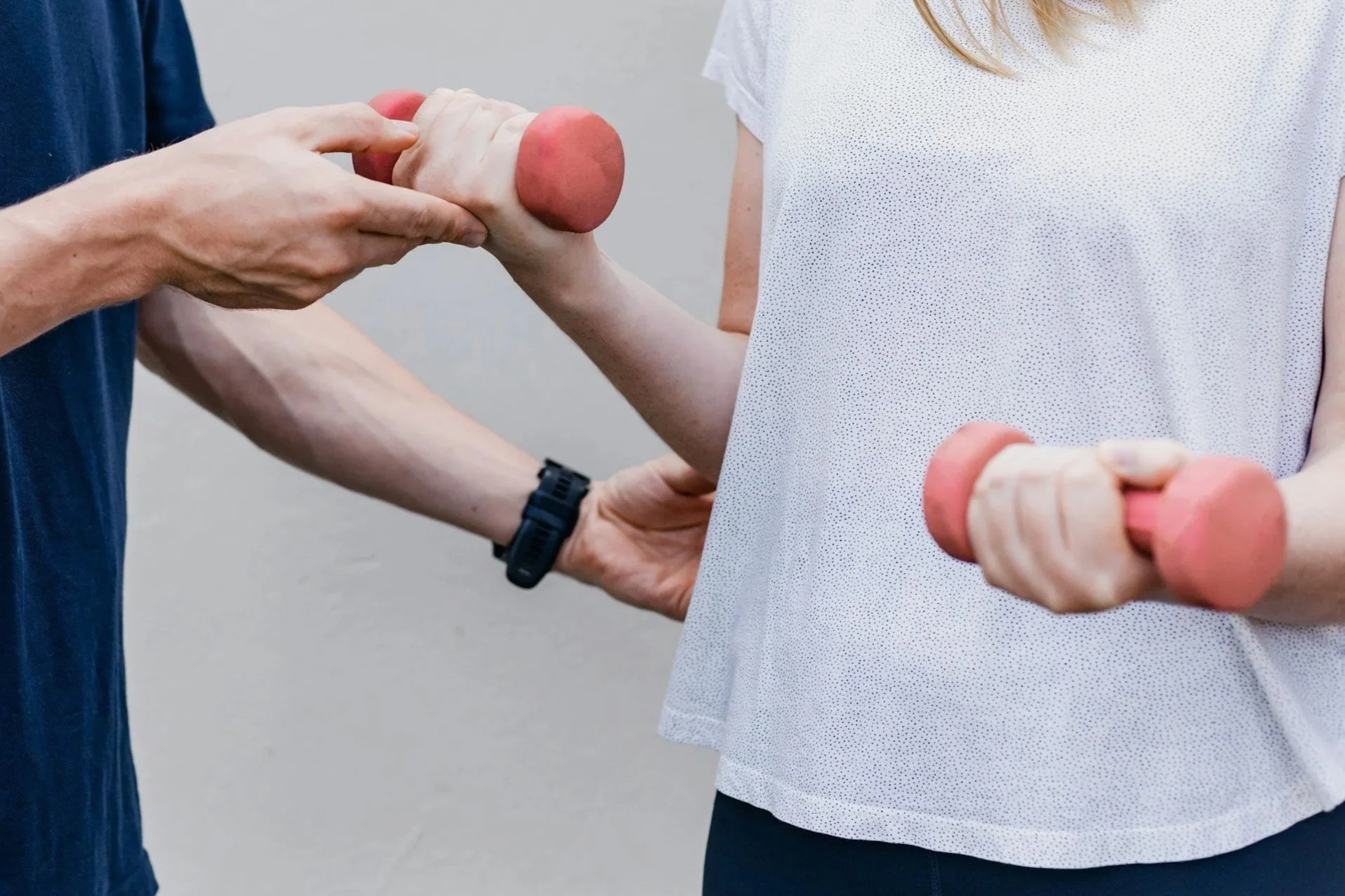 Pair of black dumbbells, a resistance band, and a jump rope with black handles on a wooden floor.