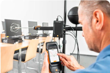 Hombre ajustando un equipo científico con un teléfono móvil en un laboratorio.